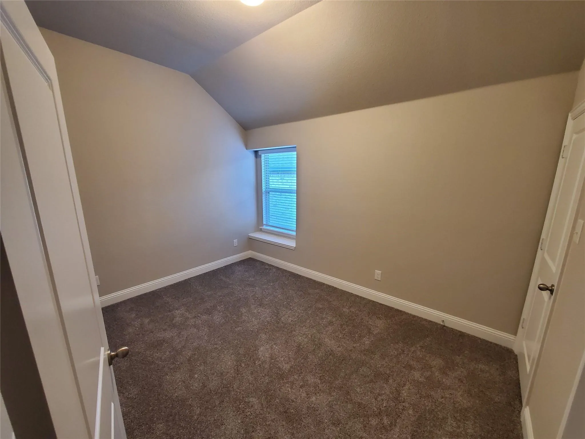 Room with textured carpet flooring, neutral wall paint, and a window with blinds