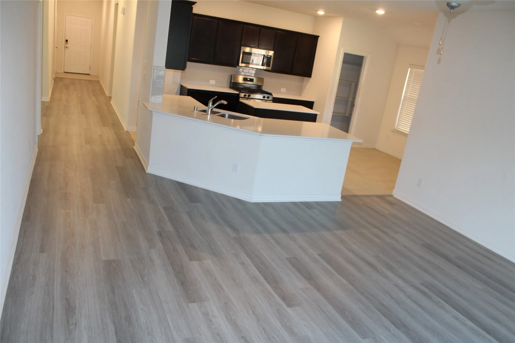 Kitchen with dark wood-finish cabinetry, stainless steel appliances, and a central island with a sink