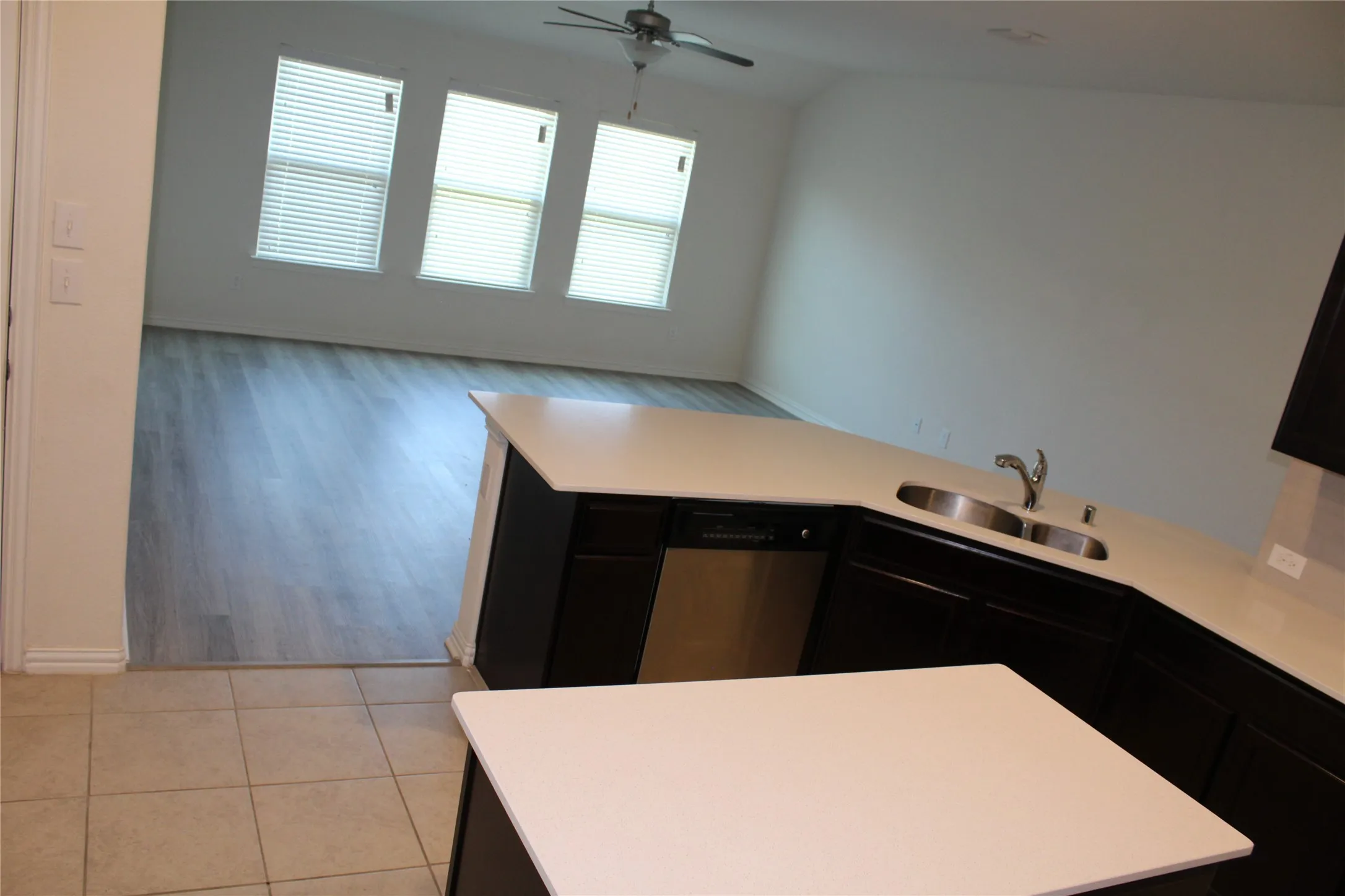 Kitchen island with solid surface countertops, stainless steel double basin sink, and stainless steel dishwasher