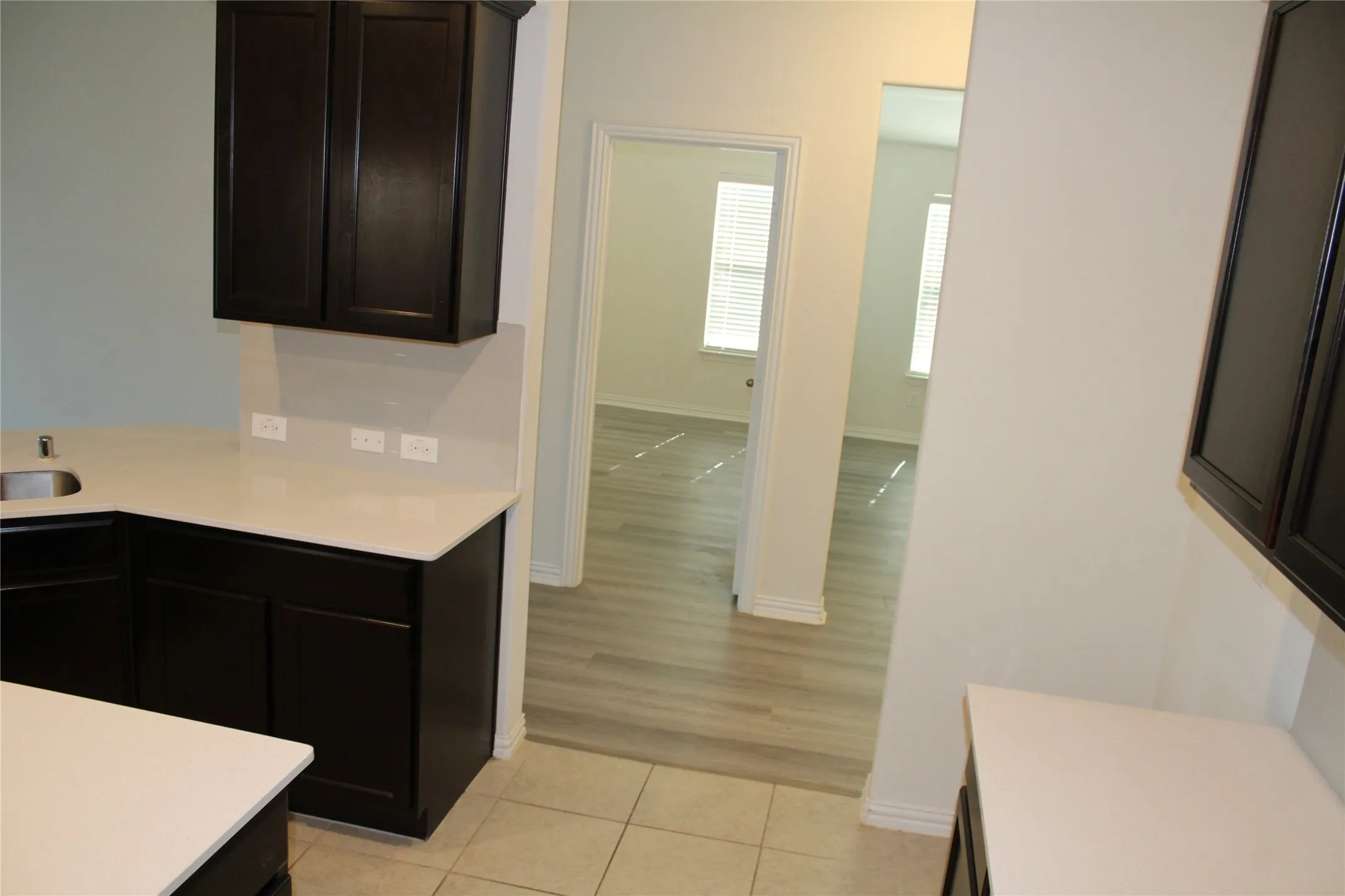 Dark wood-finish cabinetry, light-toned countertops, and a stainless steel sink