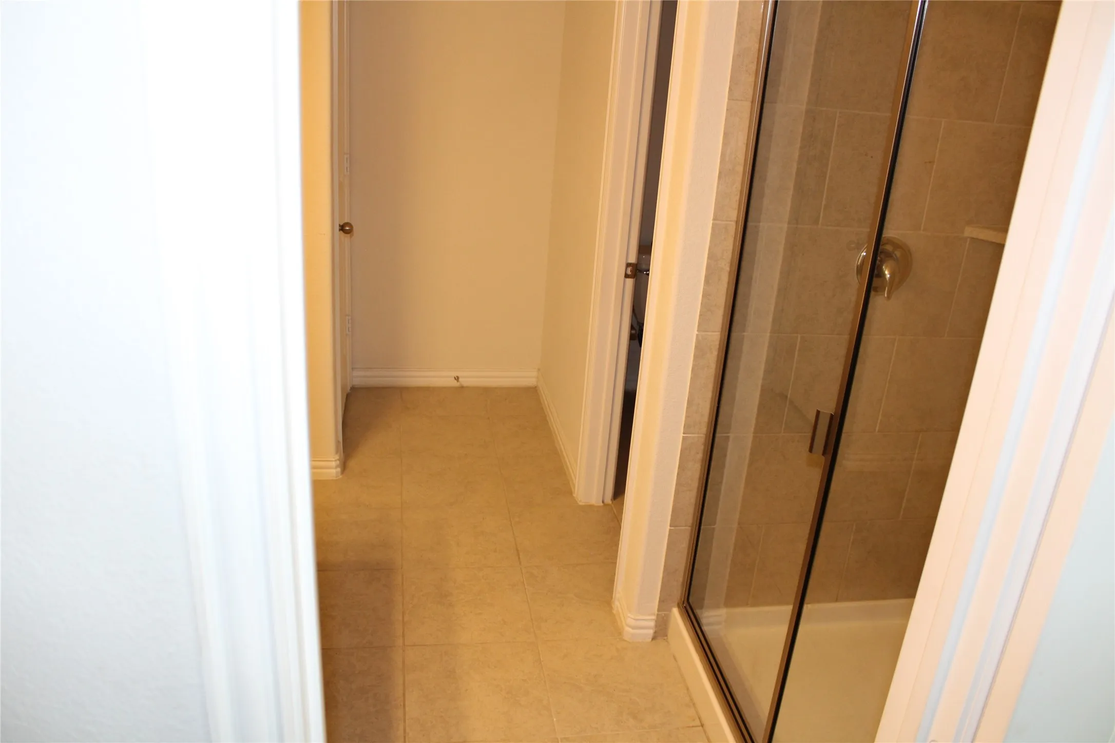Tile flooring, glass-enclosed shower with tile surround, and brushed metal fixtures