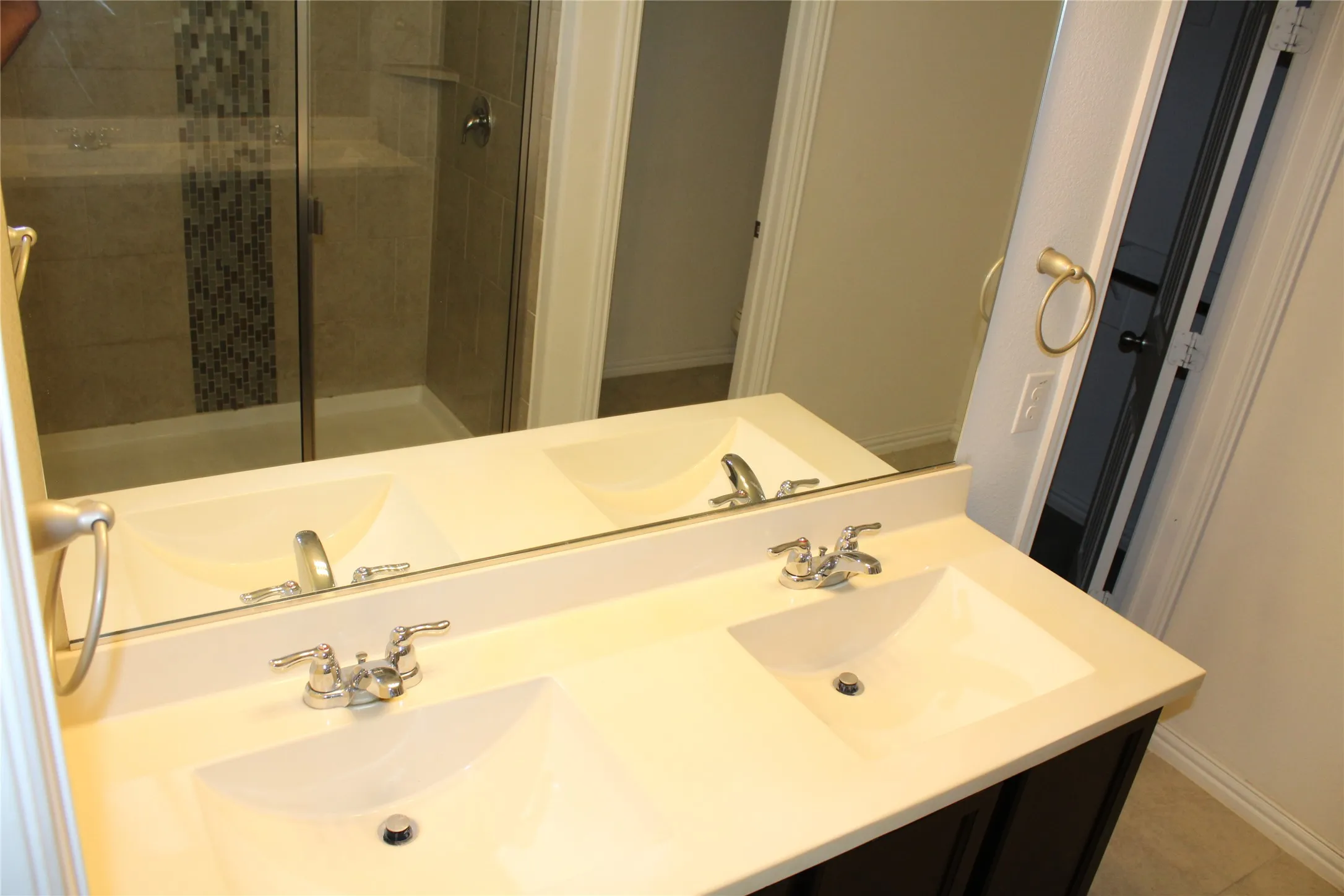 Dual integrated sinks with chrome fixtures, a spacious countertop, and a vanity-width mirror