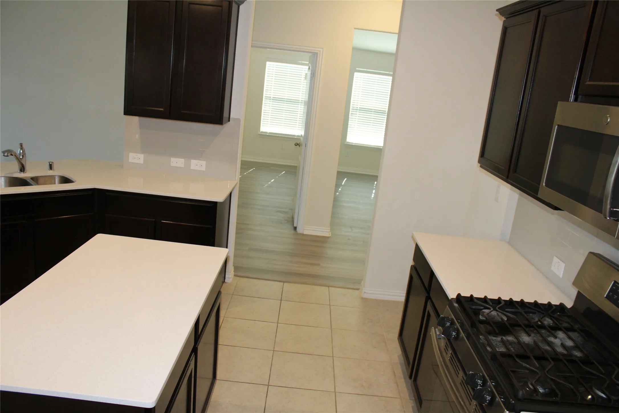 Kitchen featuring white countertops, dark wood-finish cabinetry, a stainless steel gas range, and a stainless steel microwave