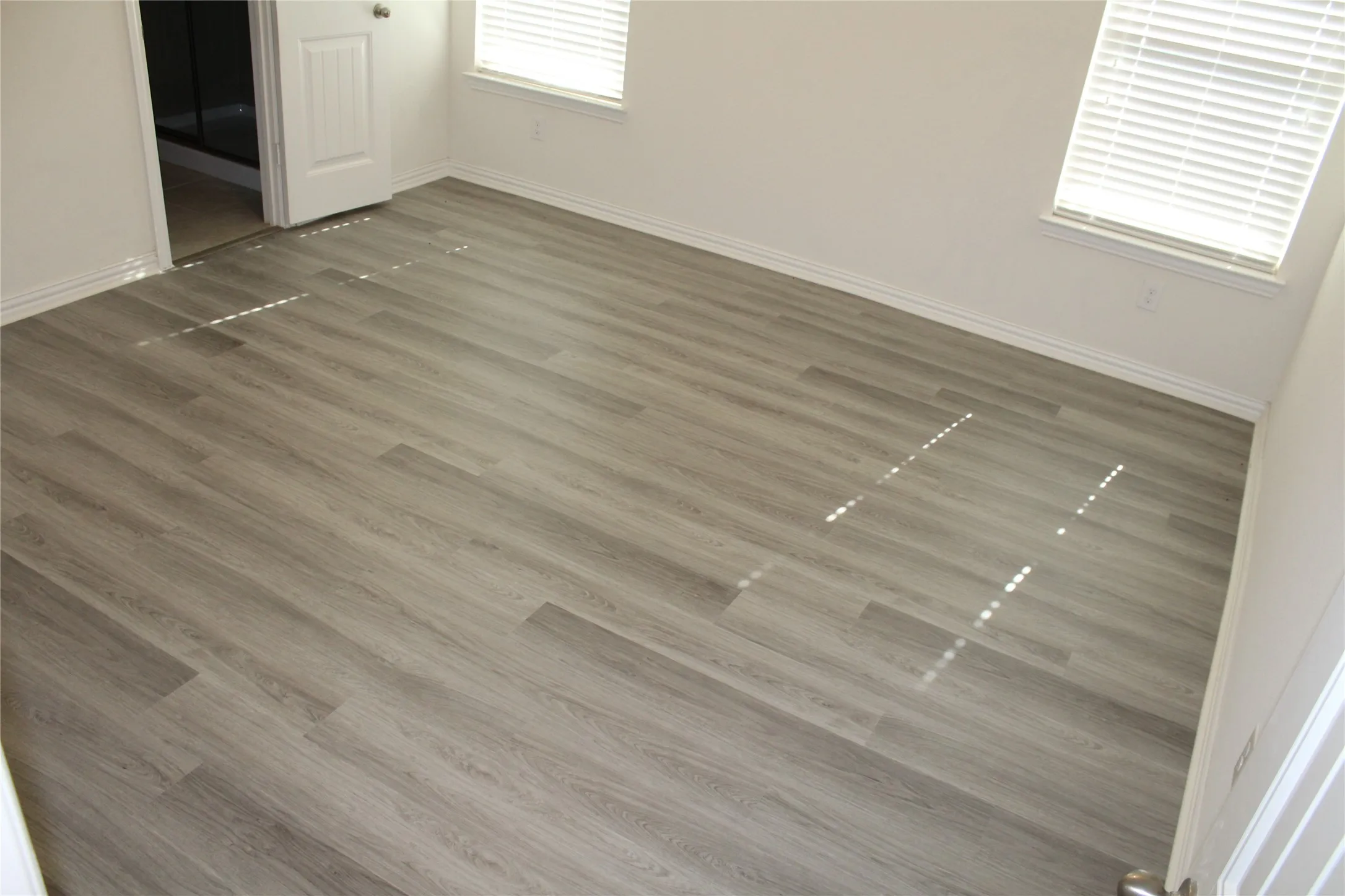 Wood-finish flooring throughout, white walls, and bright window openings