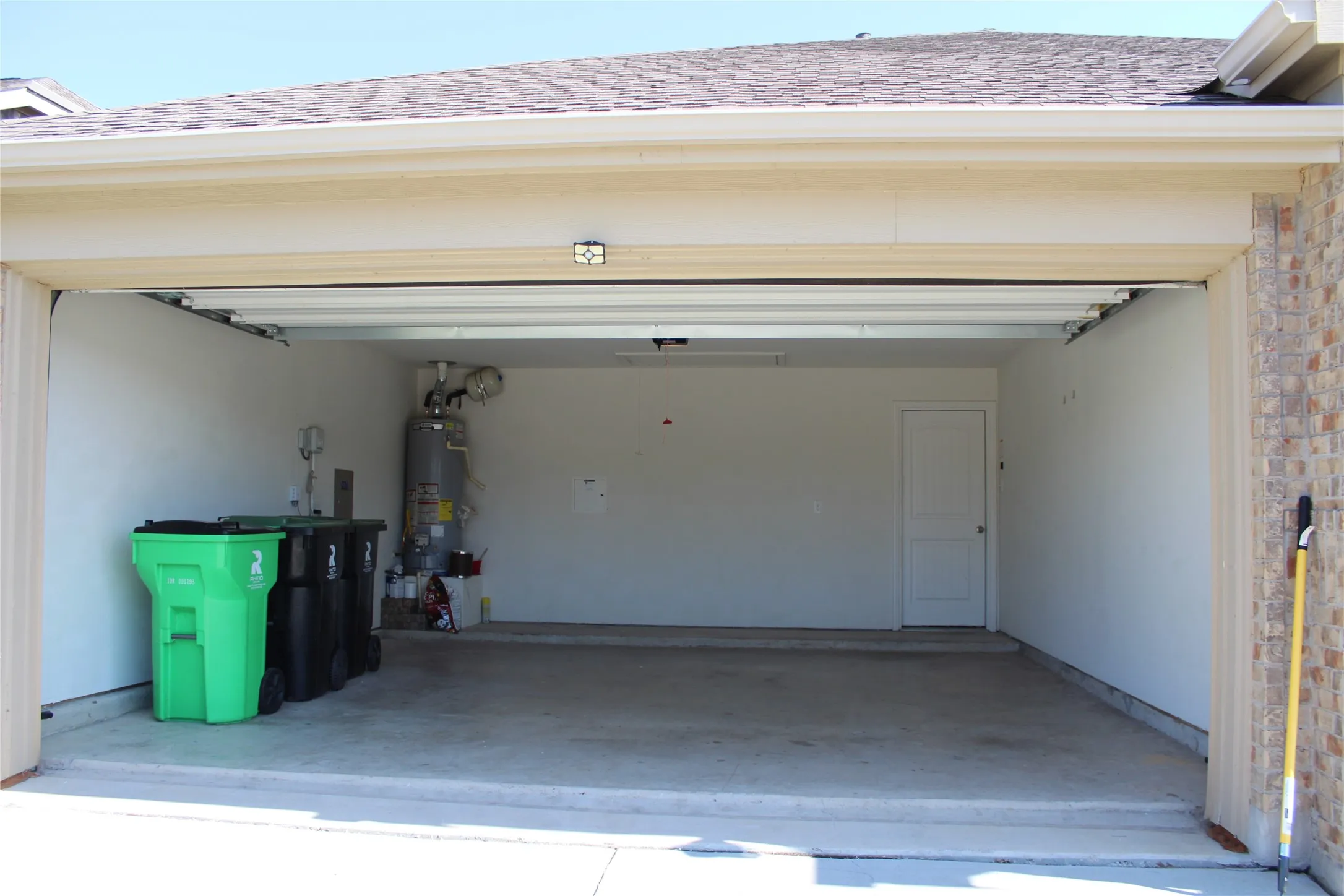 Attached garage with a concrete floor, interior access door, and a textured brick exterior facade