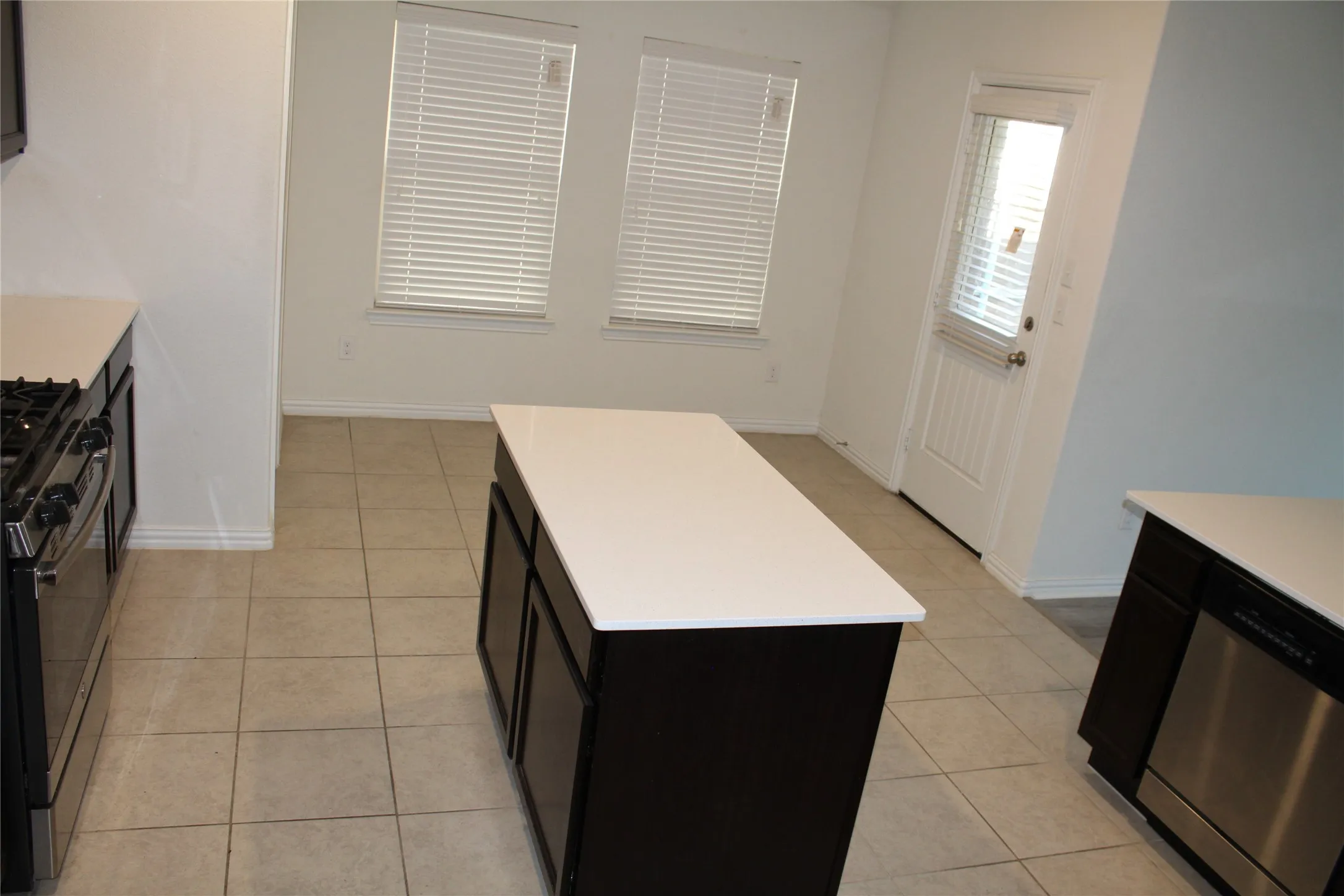 Kitchen featuring a center island, dark wood-finish cabinetry, light countertops, stainless steel appliances, and tile flooring