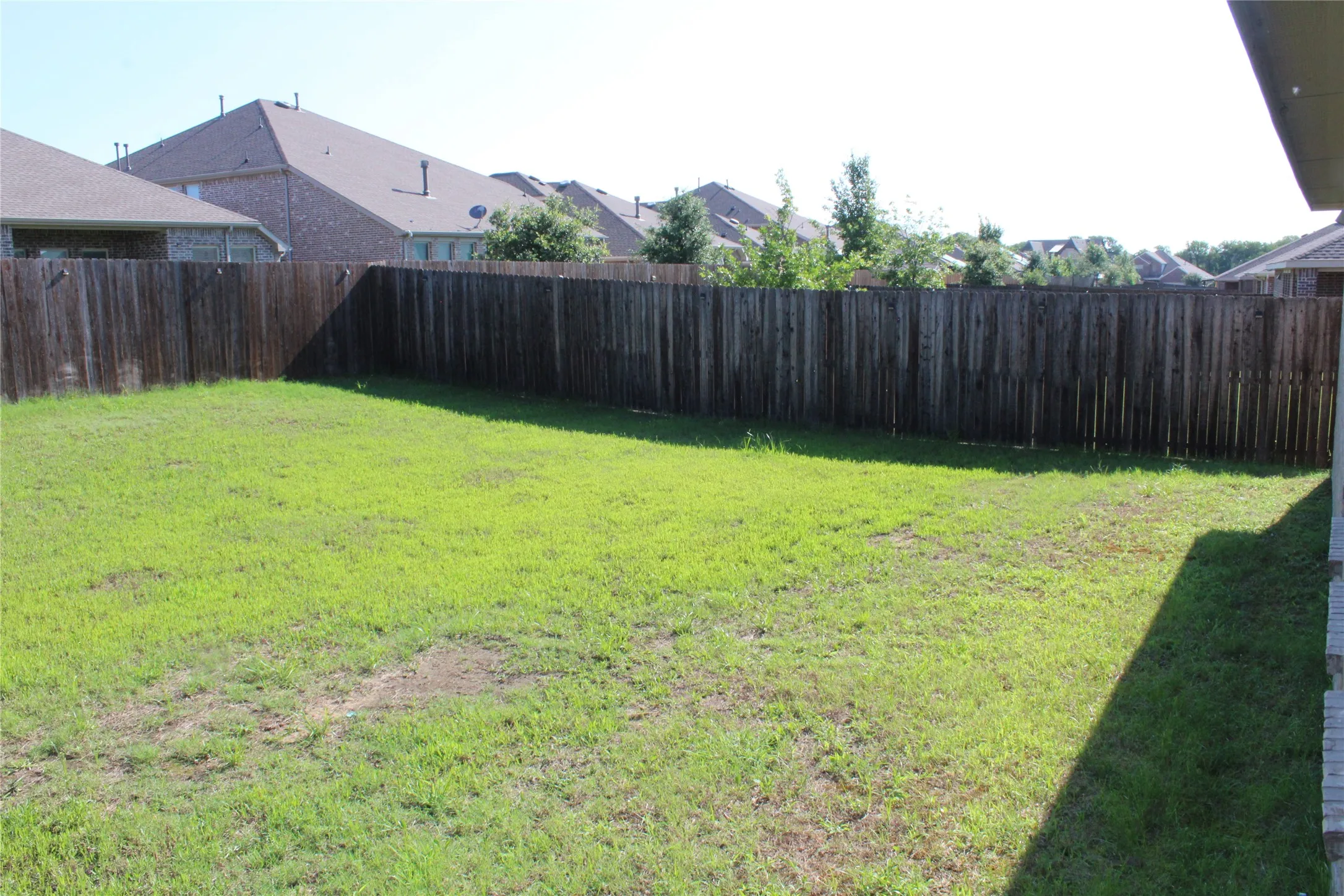 Spacious backyard featuring a full privacy fence and green lawn