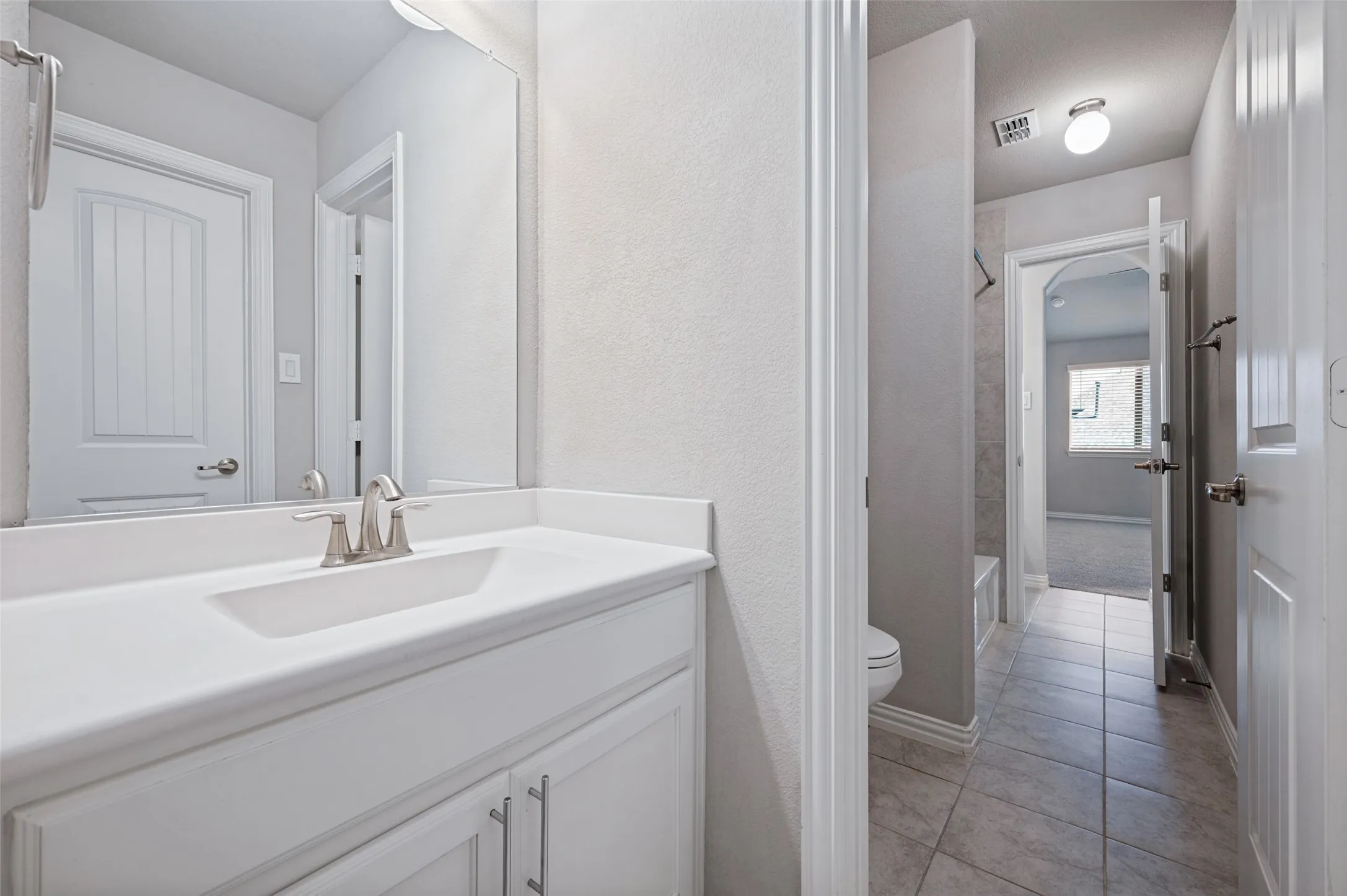Vanity with a single basin sink and brushed nickel faucet, complete with white cabinetry and a white countertop
