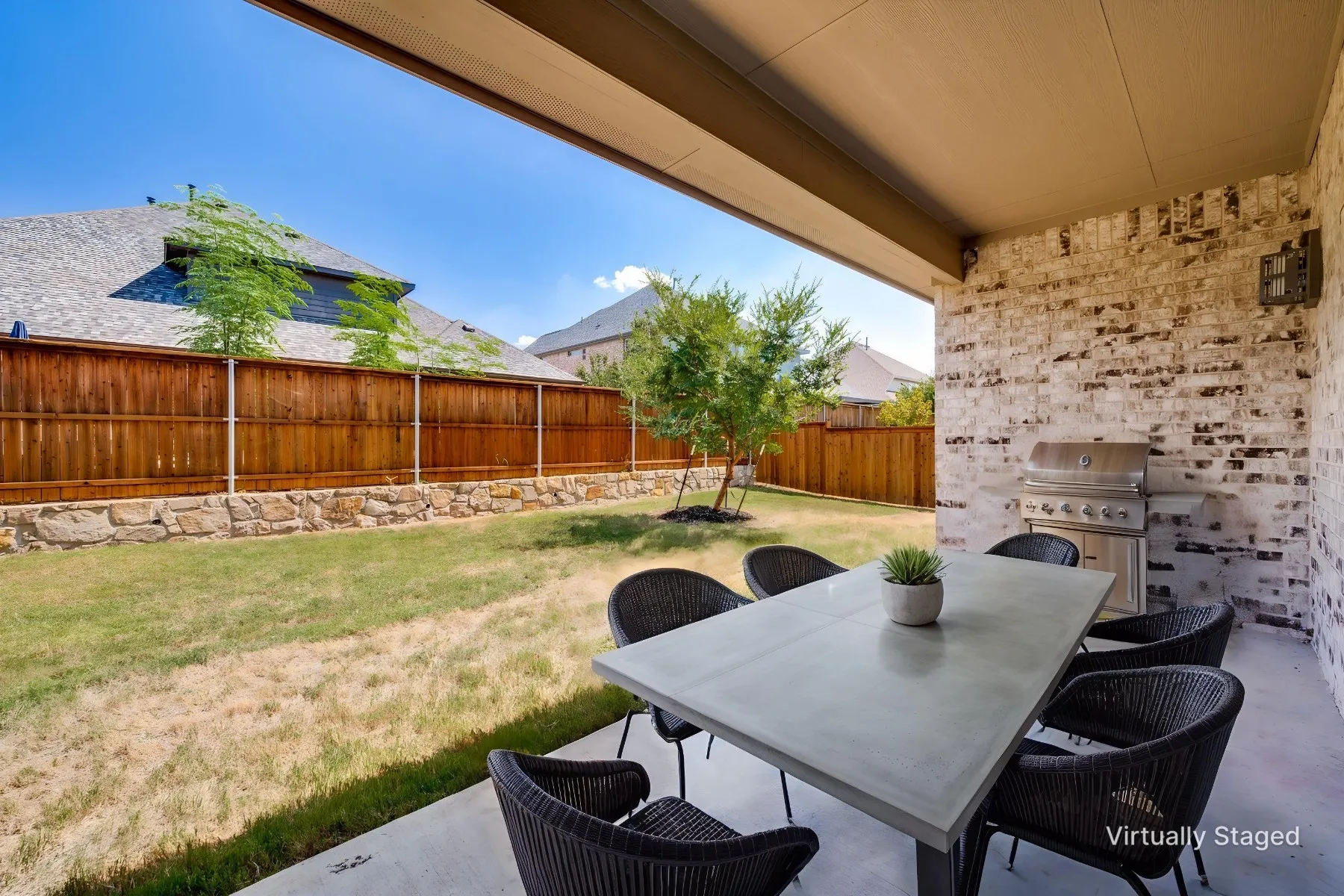 Covered patio featuring a brick accent wall and concrete flooring