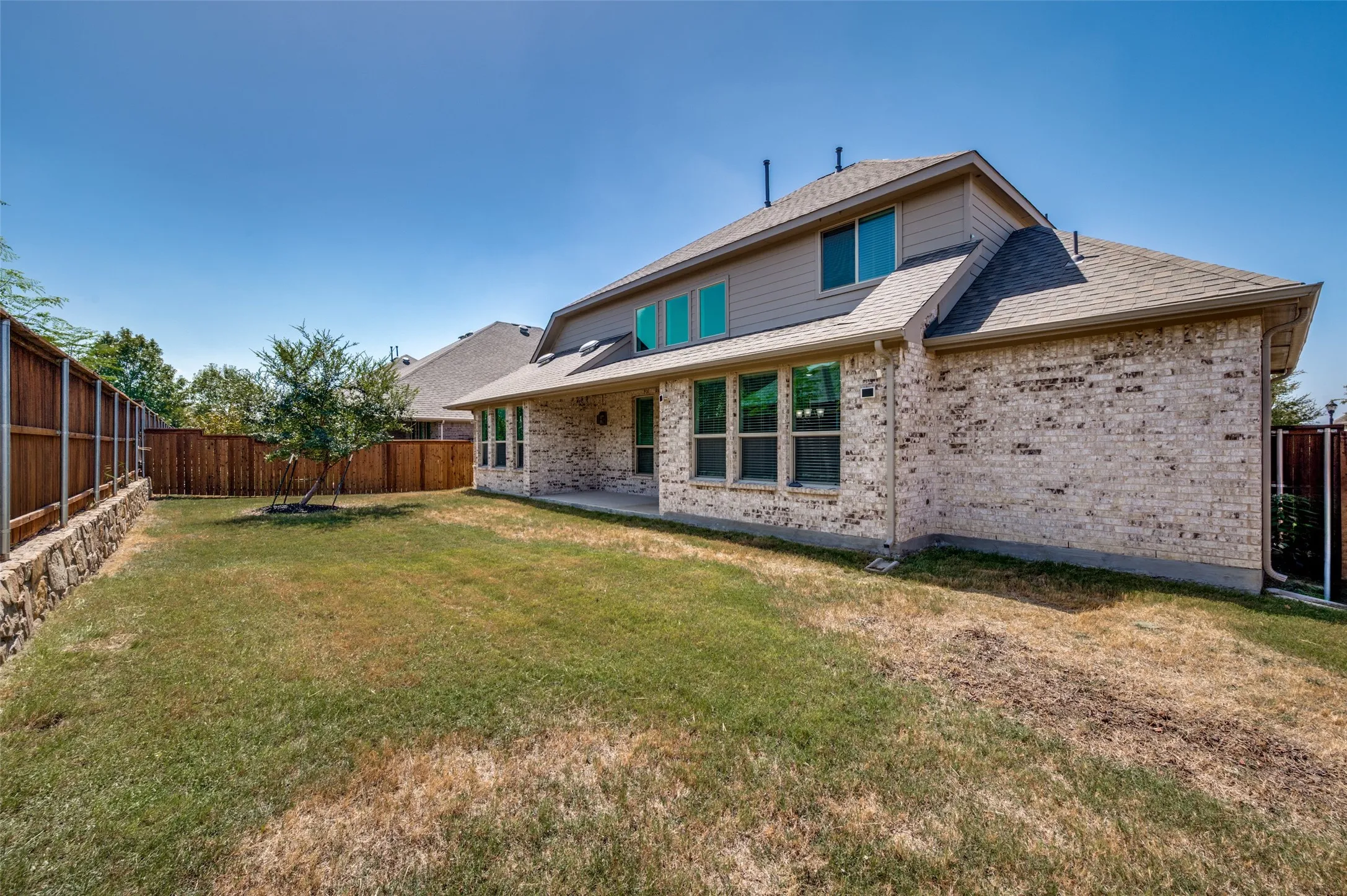 Brick exterior with a stone retaining wall and a private wood fence