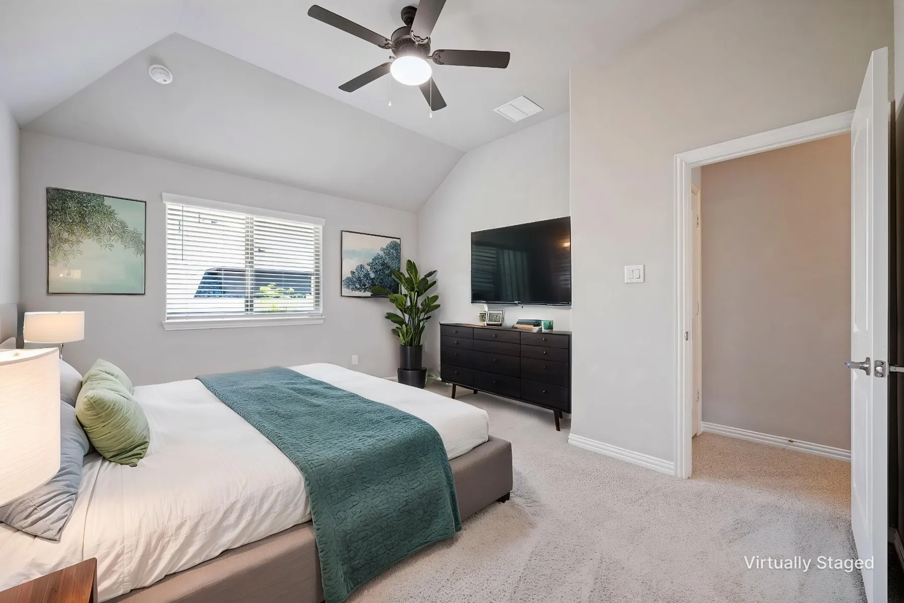 Vaulted ceiling with a ceiling fan, window with blinds, light-colored carpeting, and a built-in wall-mounted television