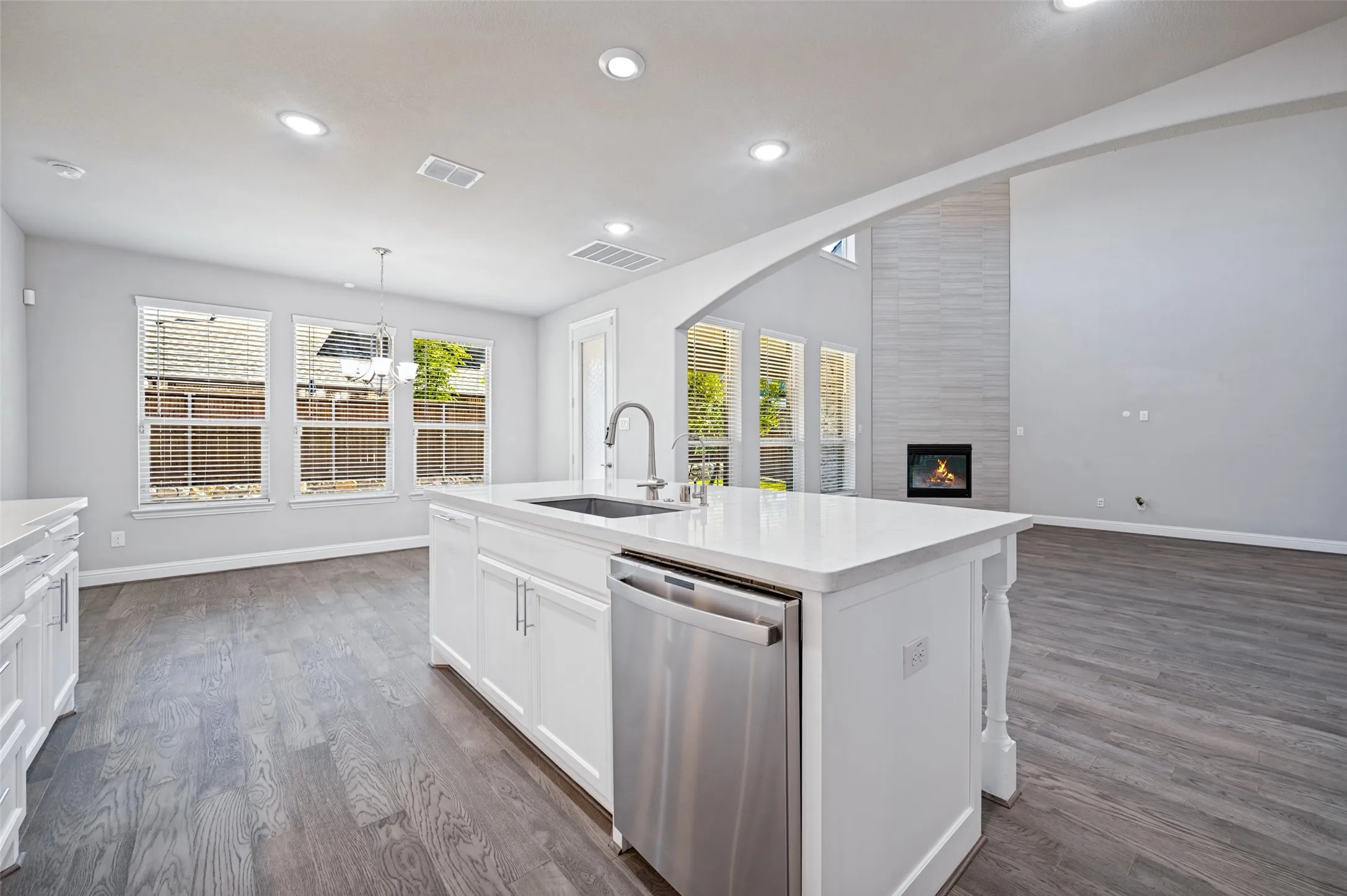 Gourmet kitchen island with white cabinetry, stainless steel sink, and dishwasher