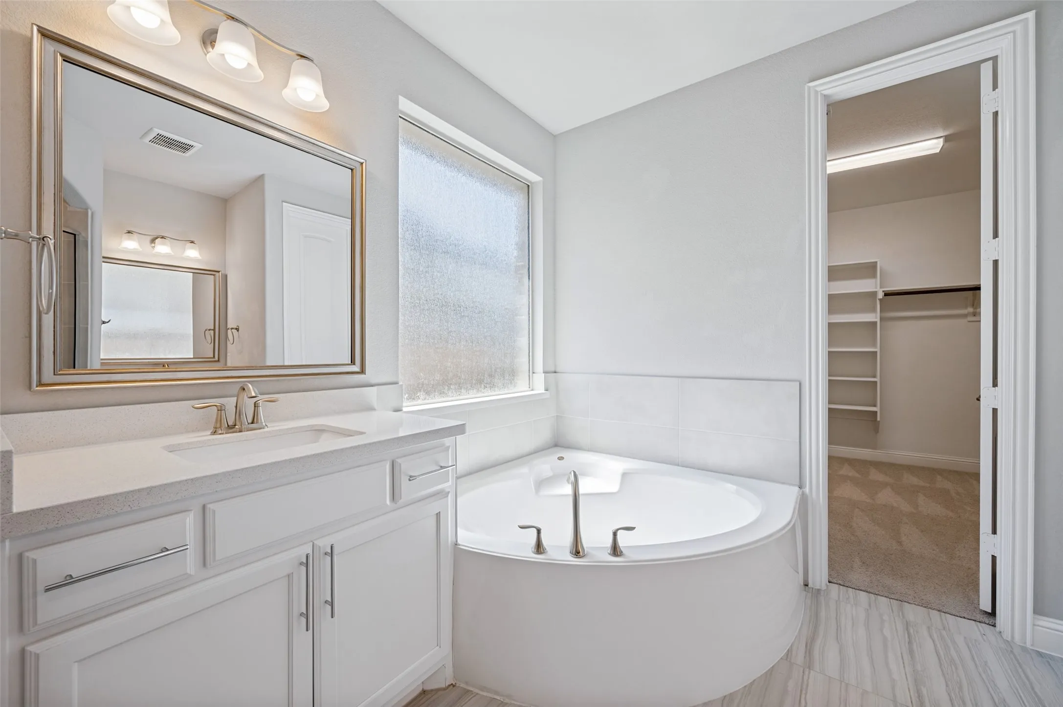 White vanity with undermount sink, brushed nickel faucet, and framed mirror