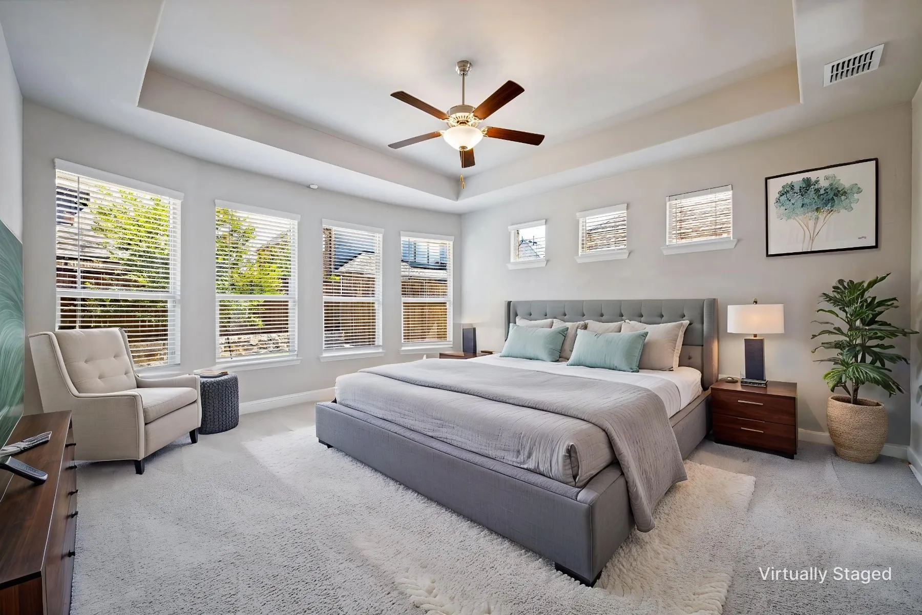 Tray ceiling with a ceiling fan, multiple windows with blinds, and light-toned carpeting