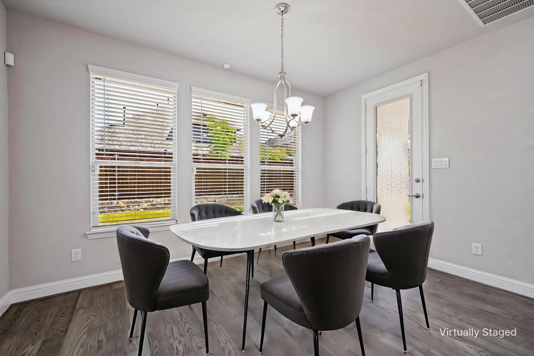 Wood-finish flooring, multiple windows with blinds, a built-in ceiling light fixture, and a glass-paneled door