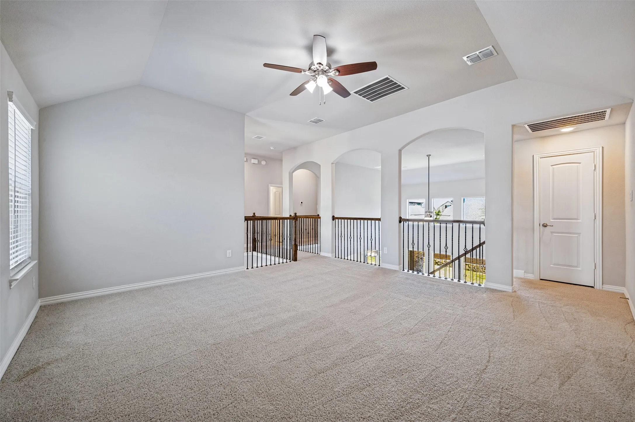 Vaulted ceiling, ceiling fan, arched doorways, carpet flooring, and white trim