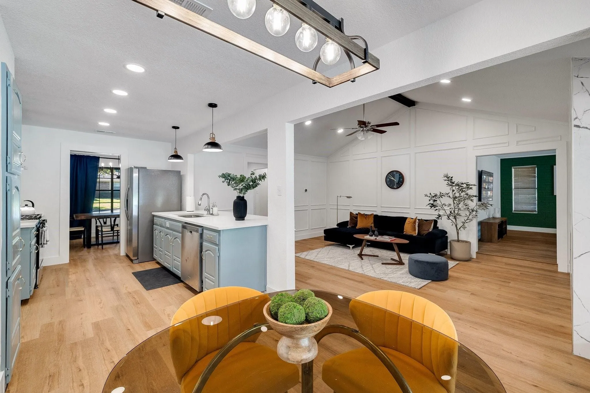 Open-concept kitchen and living area featuring wood-finish flooring, recessed lighting, and a vaulted ceiling with a decorative beam