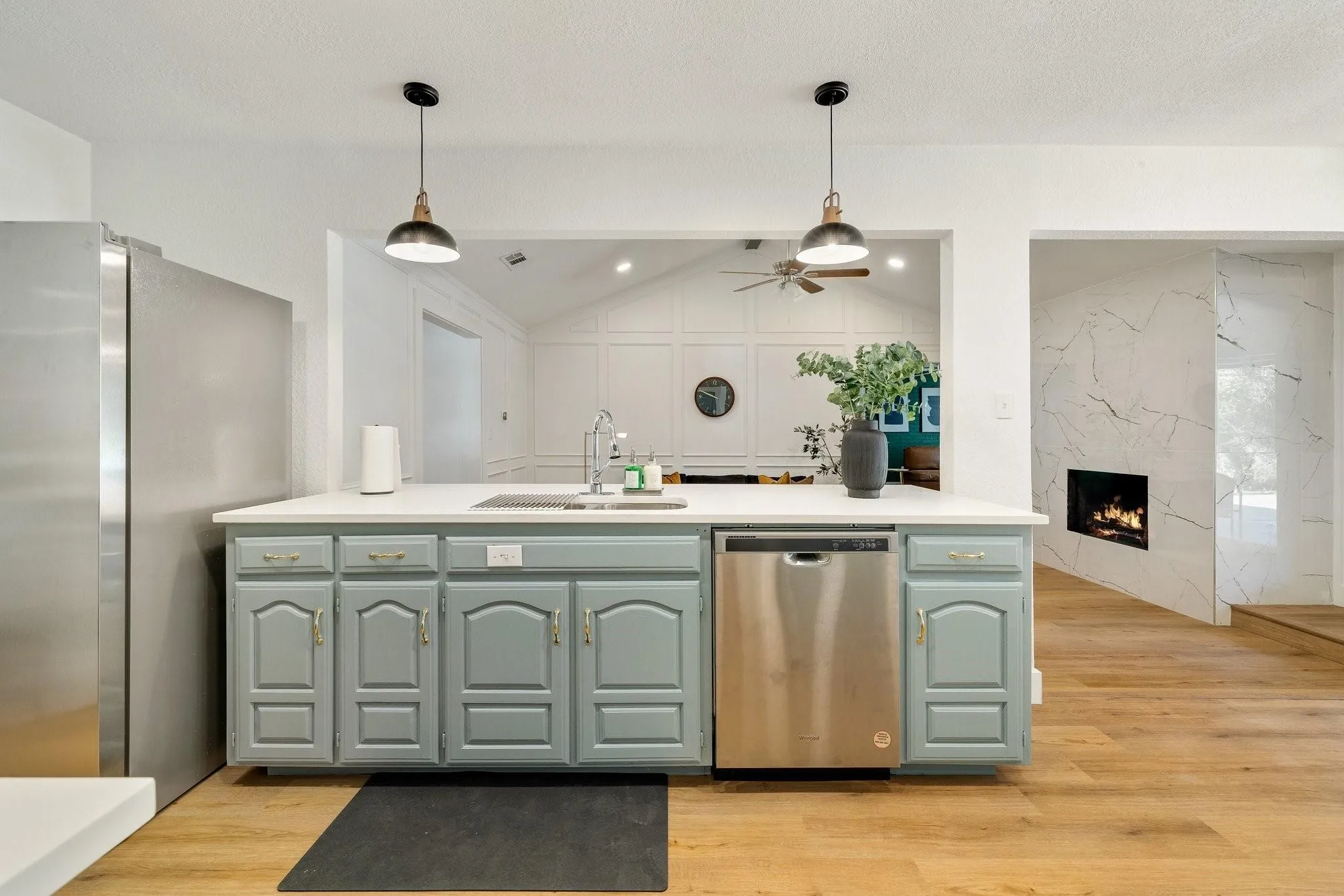 Kitchen island with light blue cabinetry, integrated stainless steel dishwasher, and white countertop