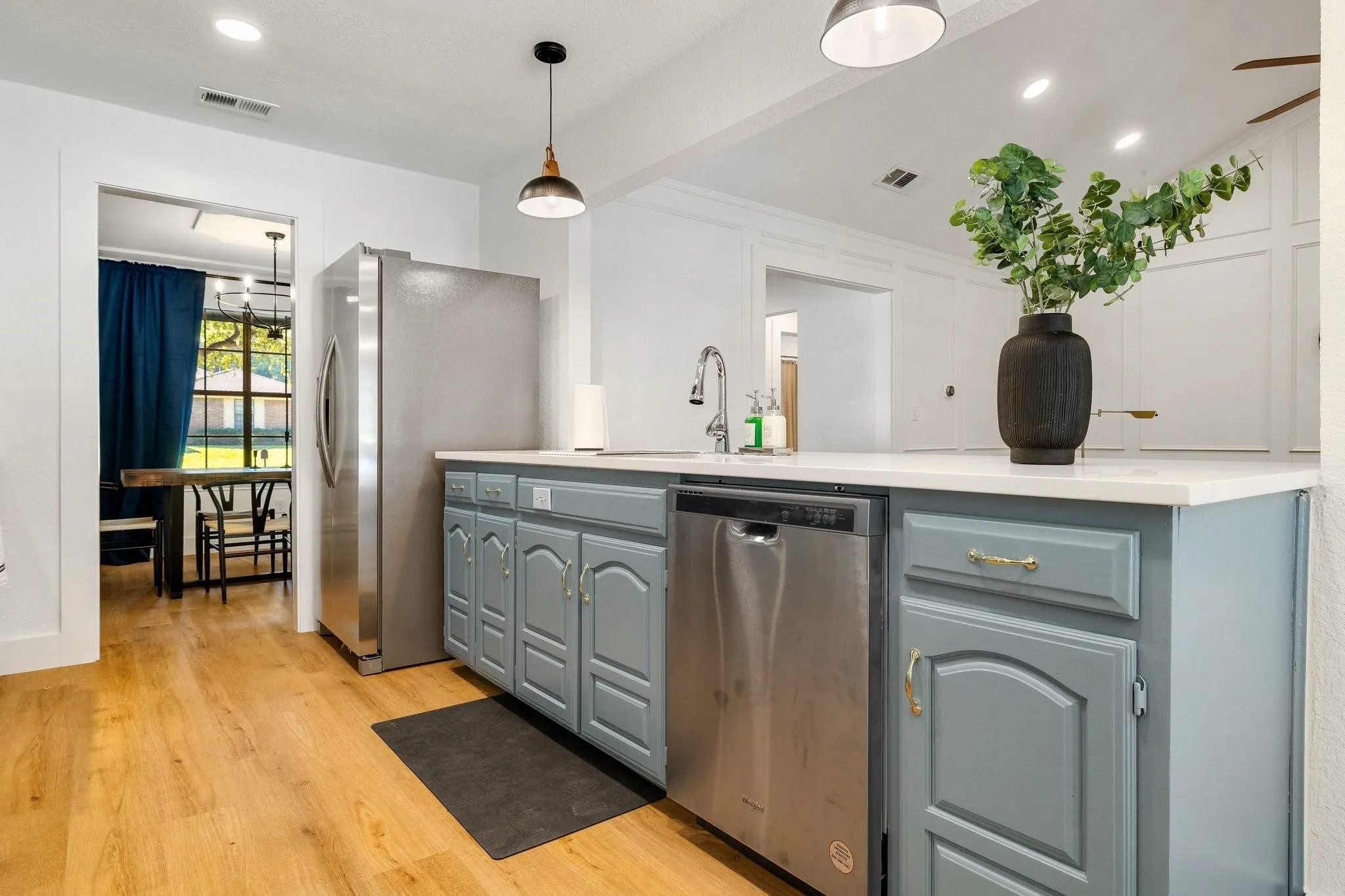 Kitchen featuring wood-finish flooring, white countertops, a stainless steel refrigerator, and a built-in stainless steel dishwasher