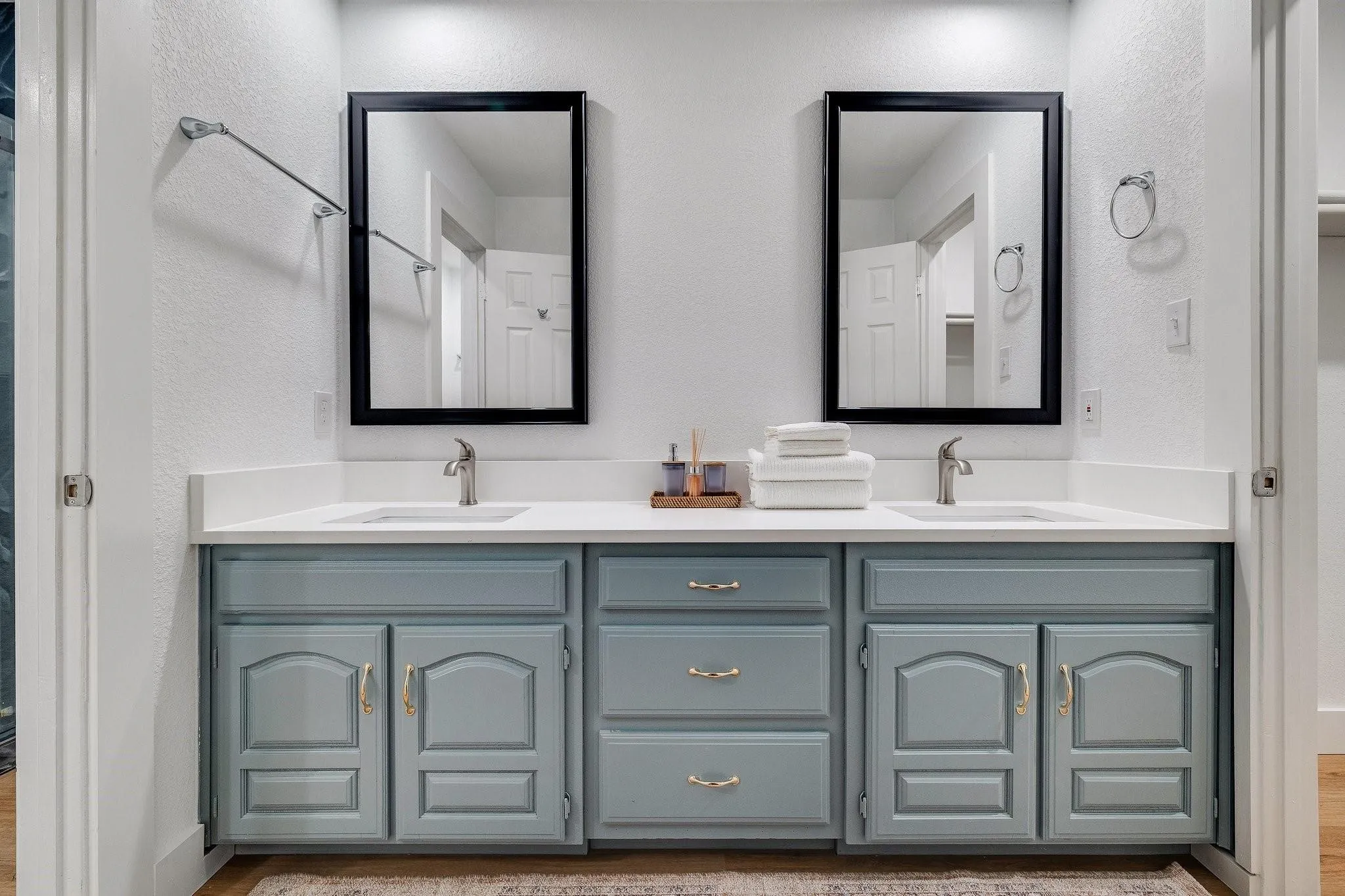 Dual vanity with light blue cabinetry, white countertops, and chrome fixtures