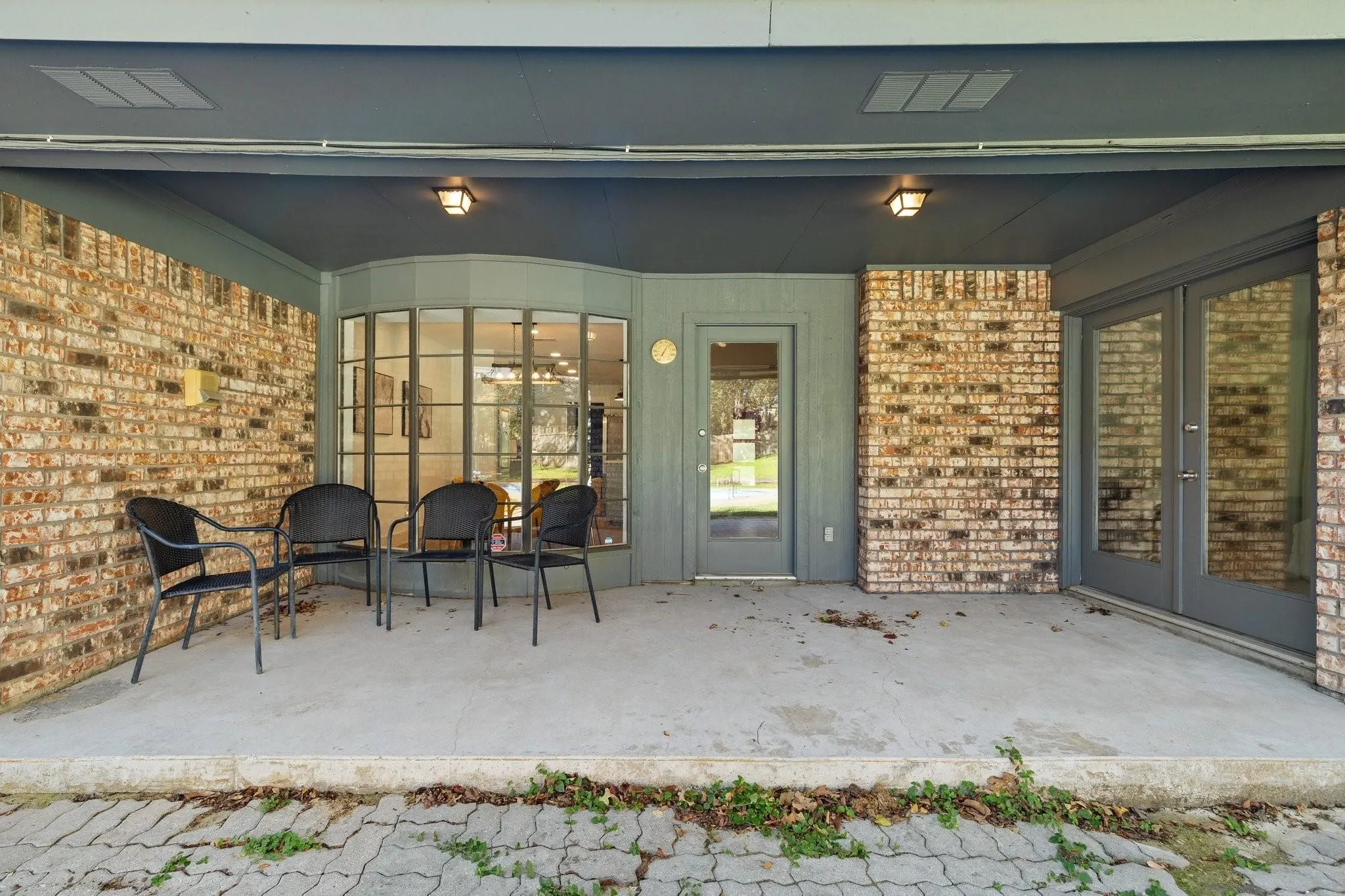 Covered concrete patio featuring brick walls