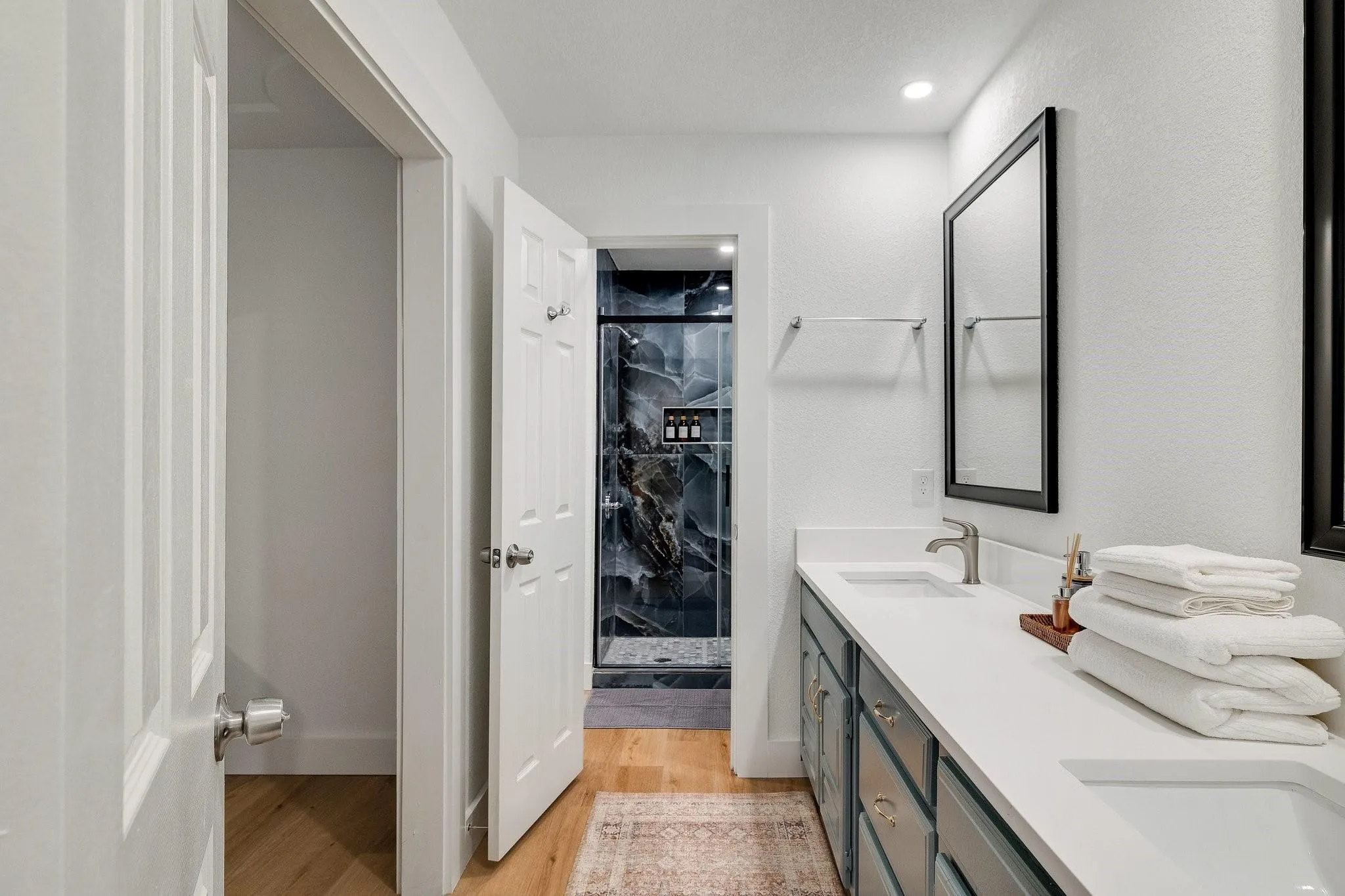 Dual sink vanity with white countertop, brushed nickel fixtures, and dark-paneled cabinetry