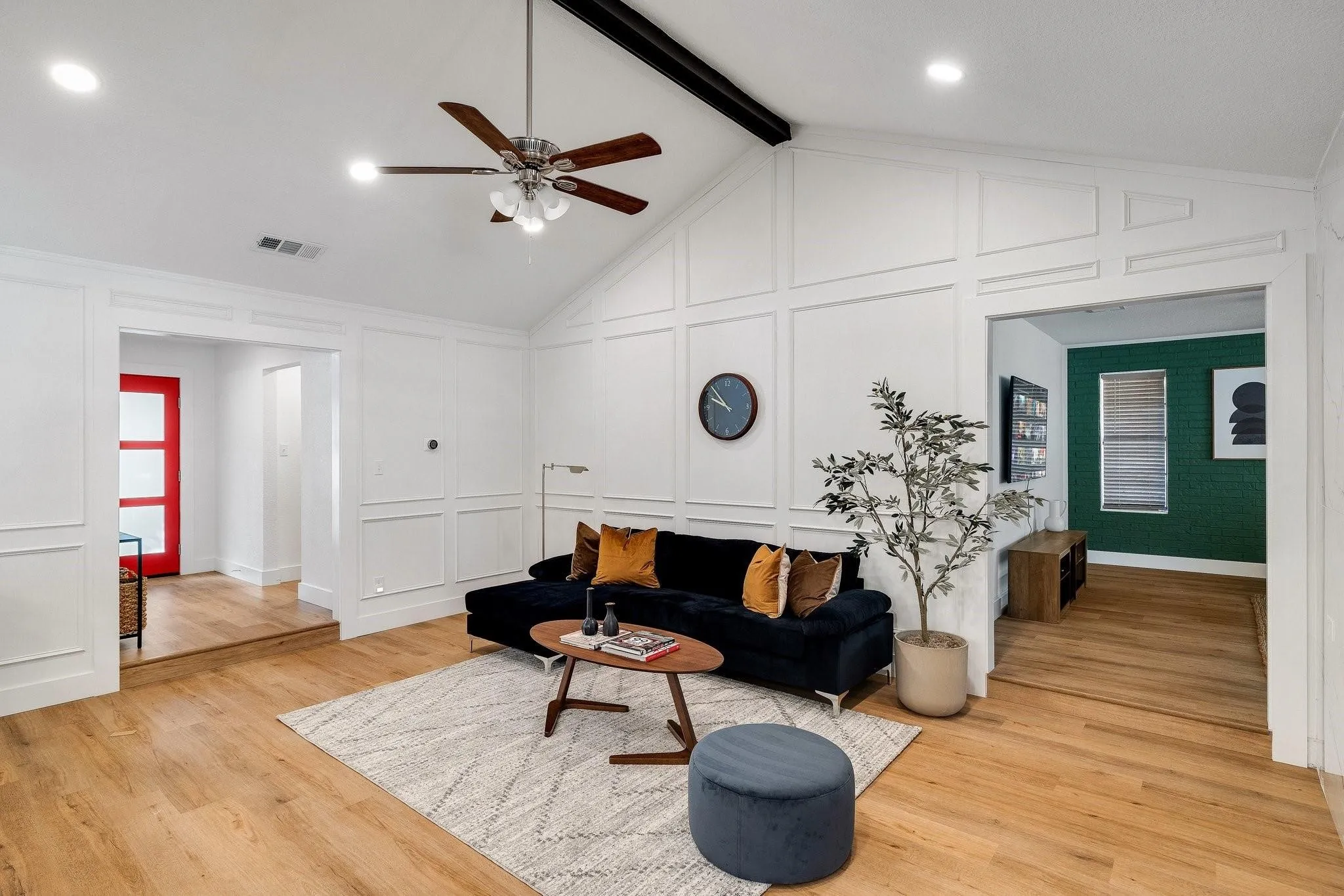 Vaulted ceiling with exposed beam, wood-finish flooring, white paneled wall detailing, recessed lighting, and a modern ceiling fan