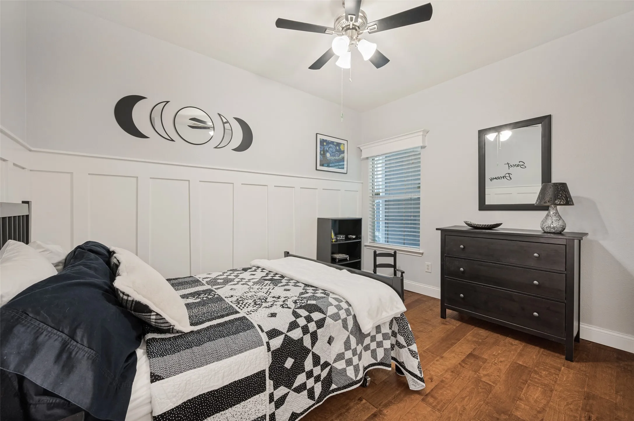 Wood-finish flooring, ceiling fan with integrated lighting, wall paneling, and window with blinds