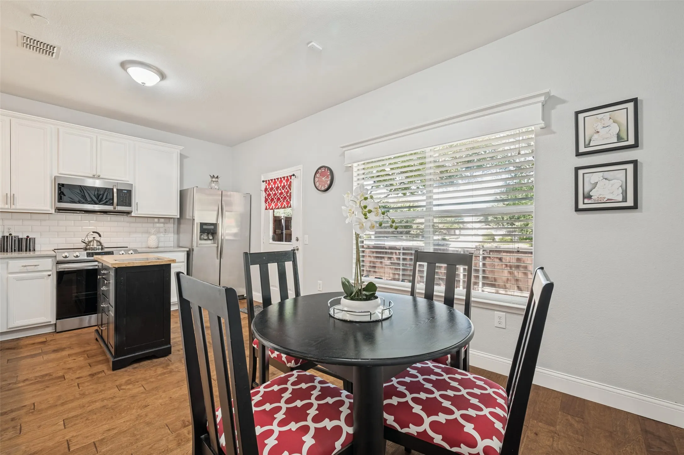 Kitchen with white cabinetry, stainless steel appliances, subway tile backsplash, and wood-finish flooring