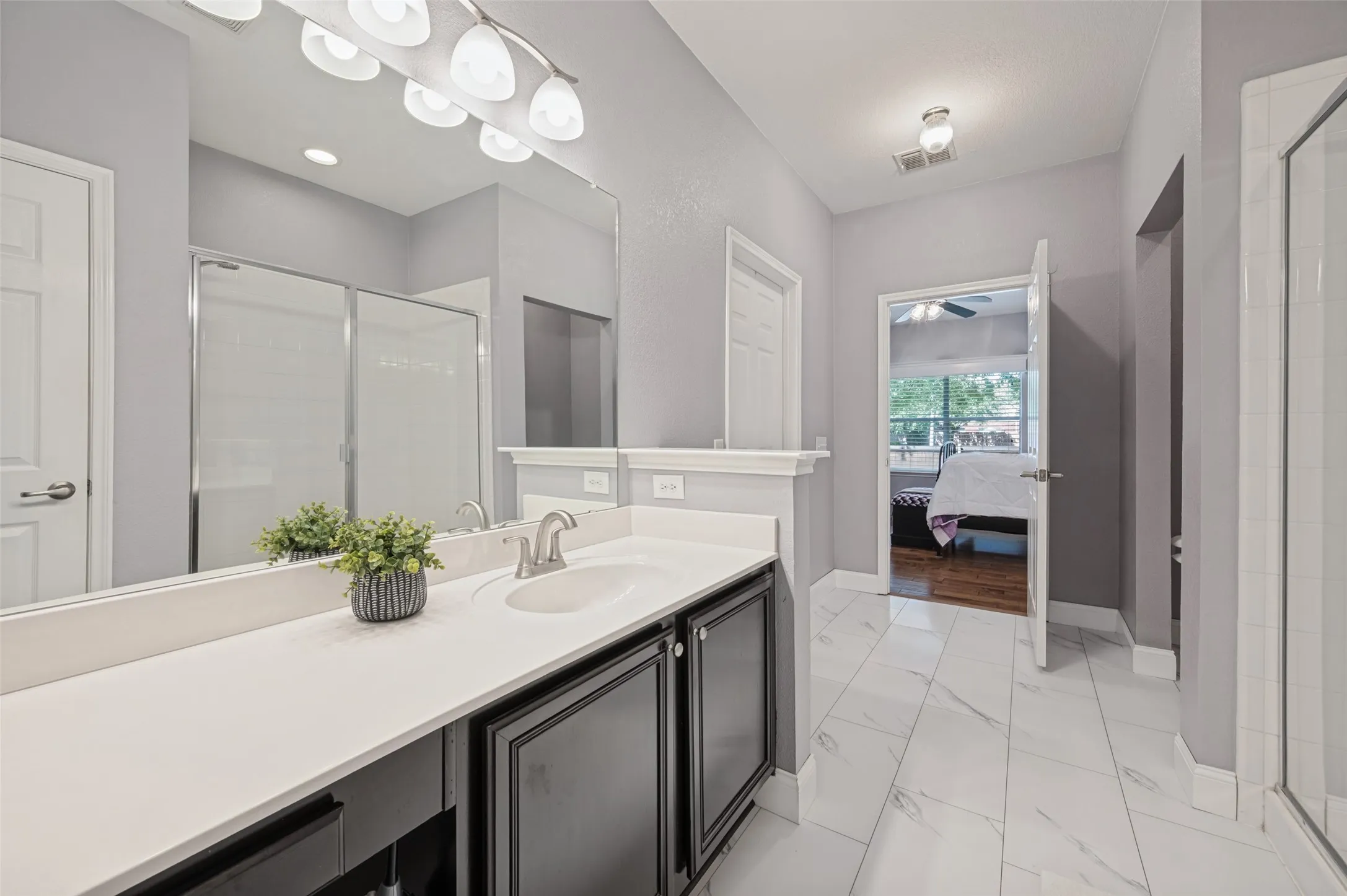 Vanity with a white countertop and undermount sink, dark wood-finish cabinetry, and a full-width mirror