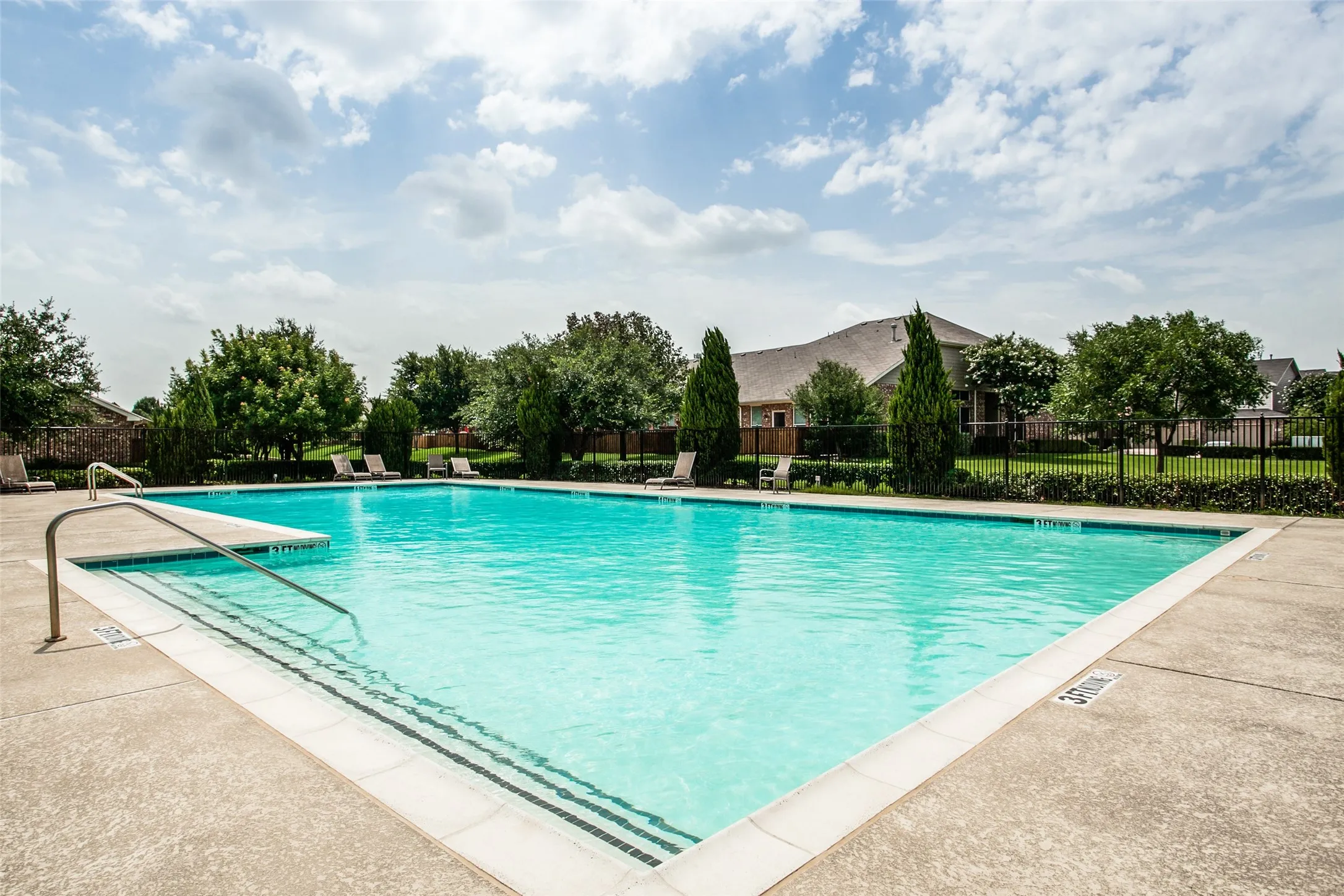 Rectangular swimming pool with concrete decking and perimeter fencing