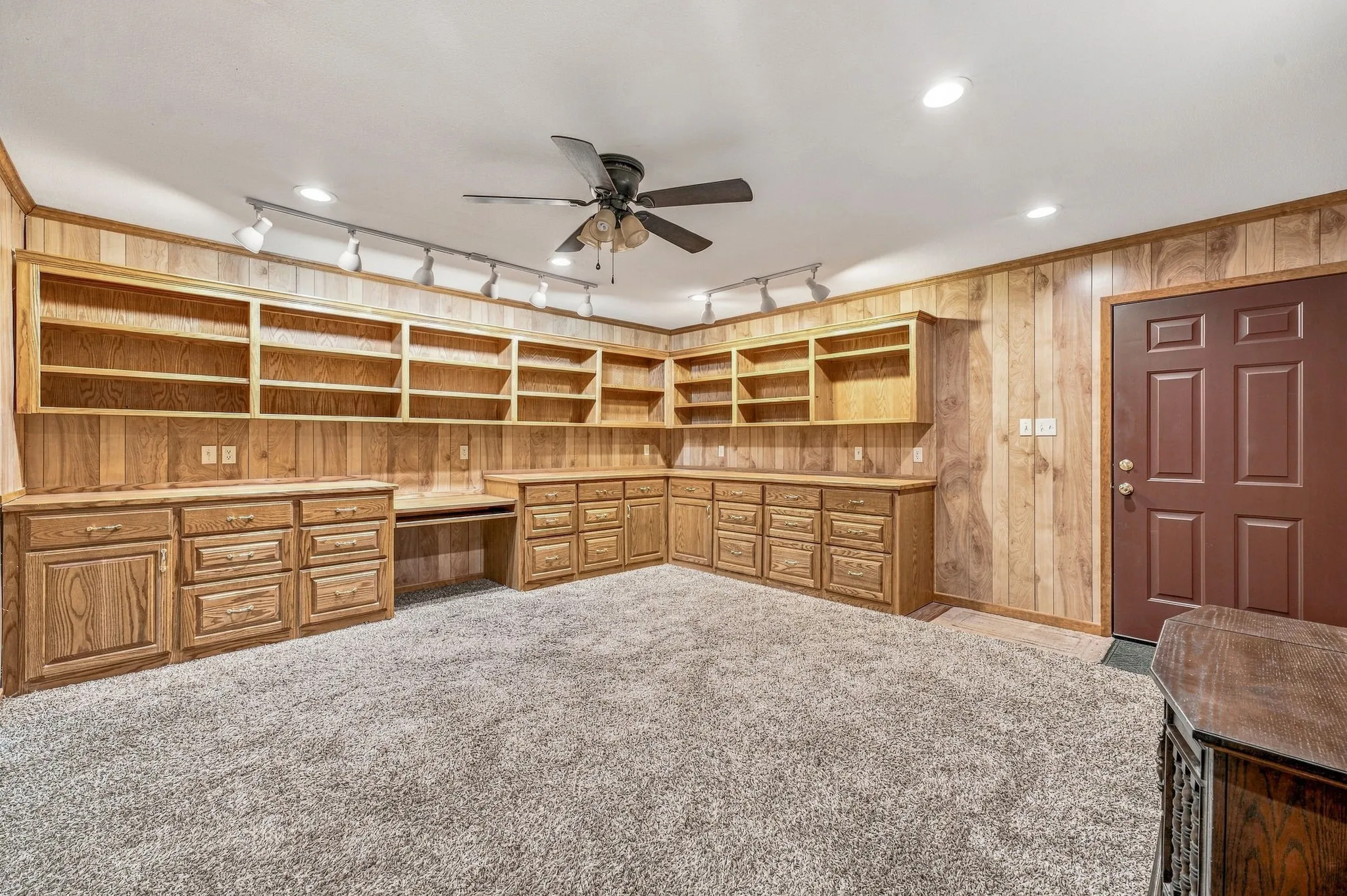 Built-in wood cabinetry with integrated shelving and desk space, track lighting, and a ceiling fan