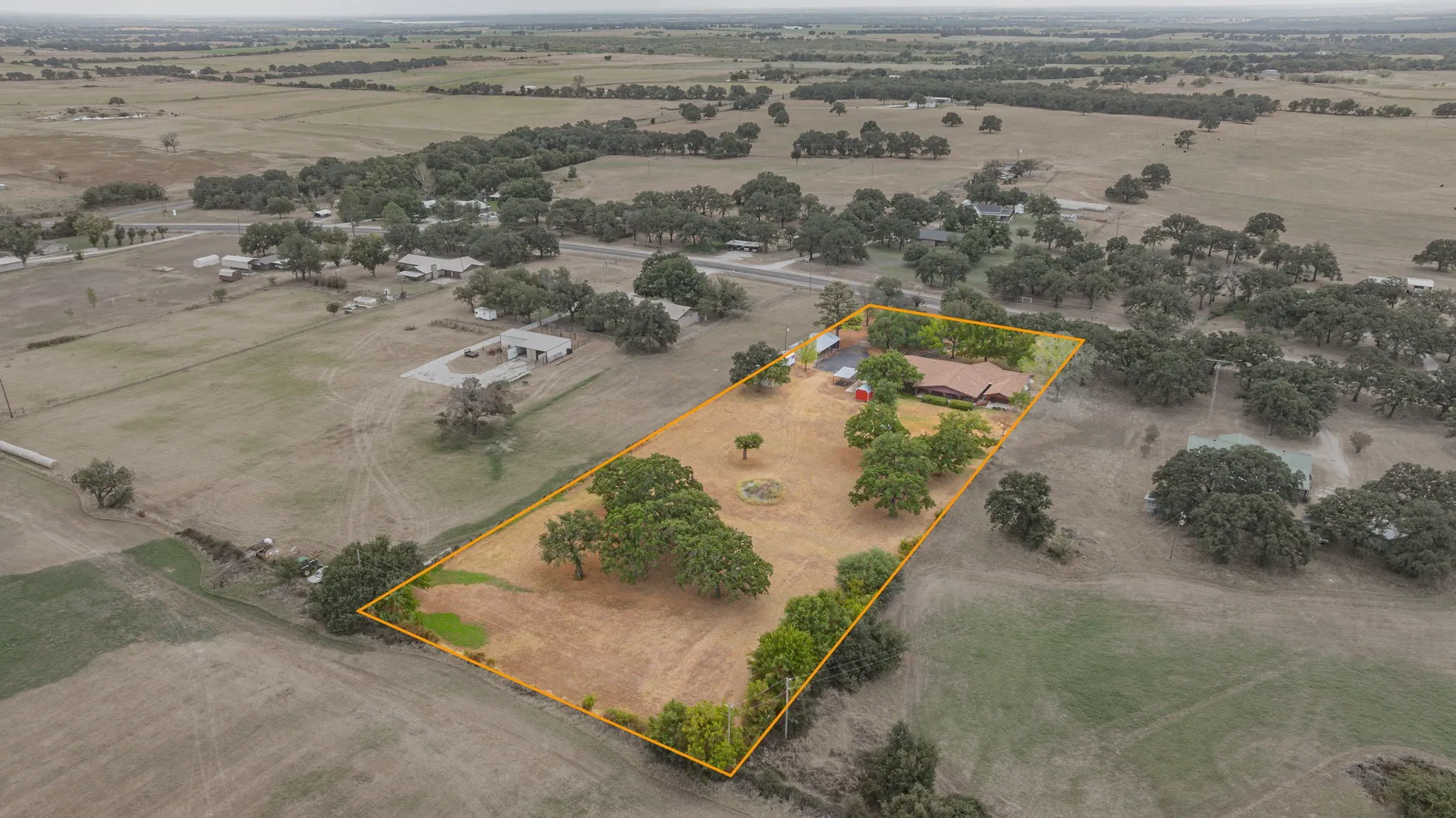 Expansive property featuring a single-story residence, multiple outbuildings, and mature trees across a substantial land parcel