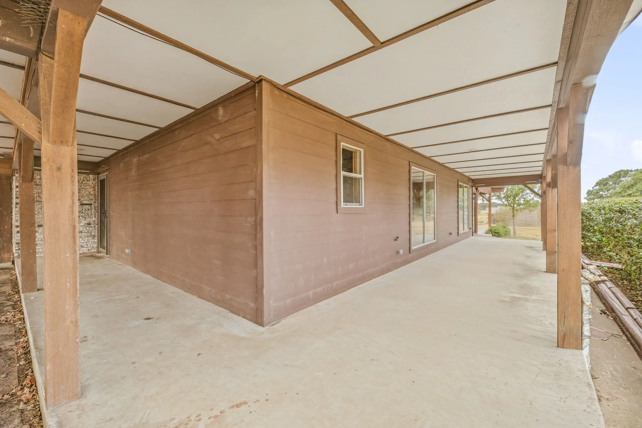 Expansive covered patio with concrete flooring and wood support beams