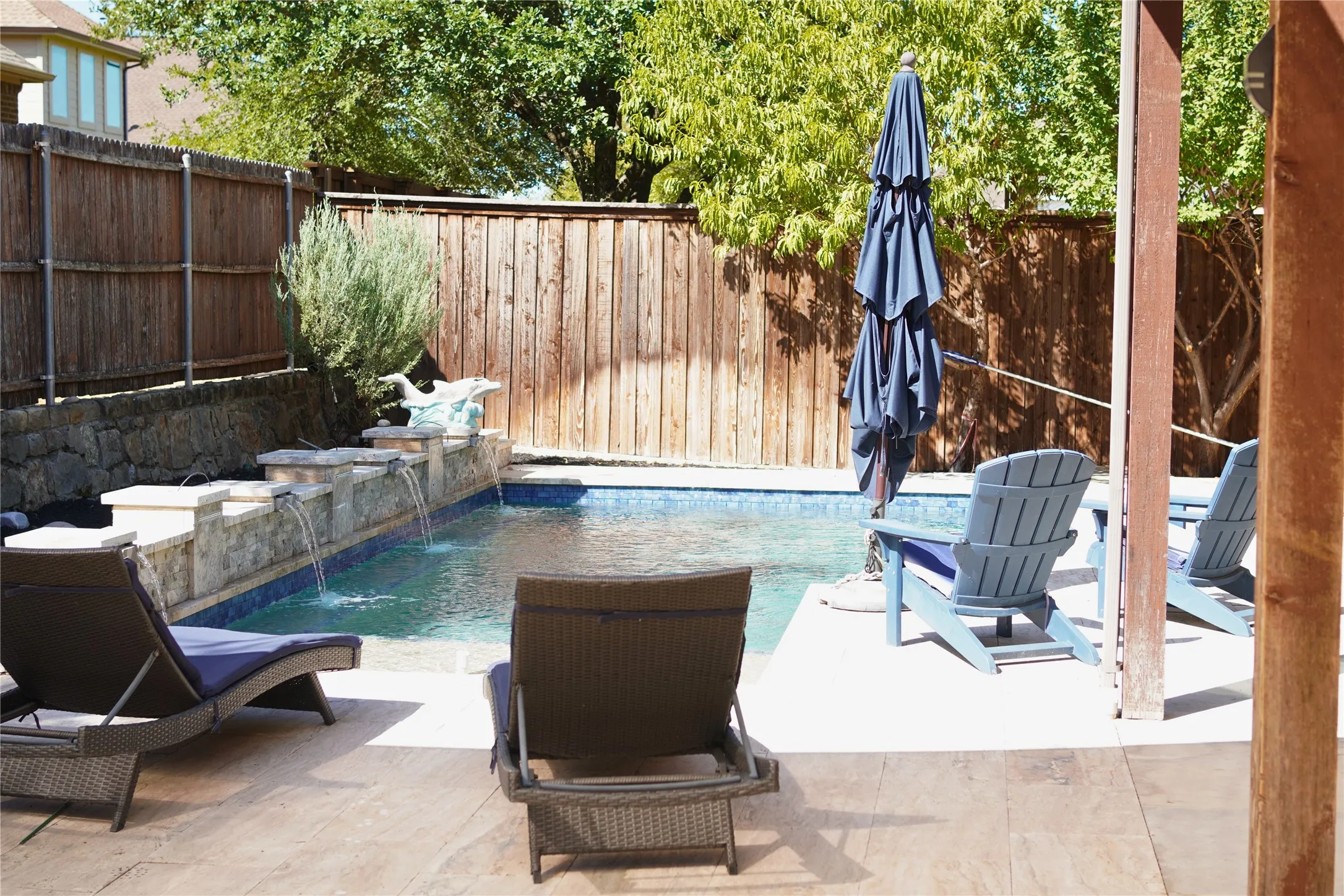 Private backyard featuring a swimming pool, integrated water features, and a stone retaining wall