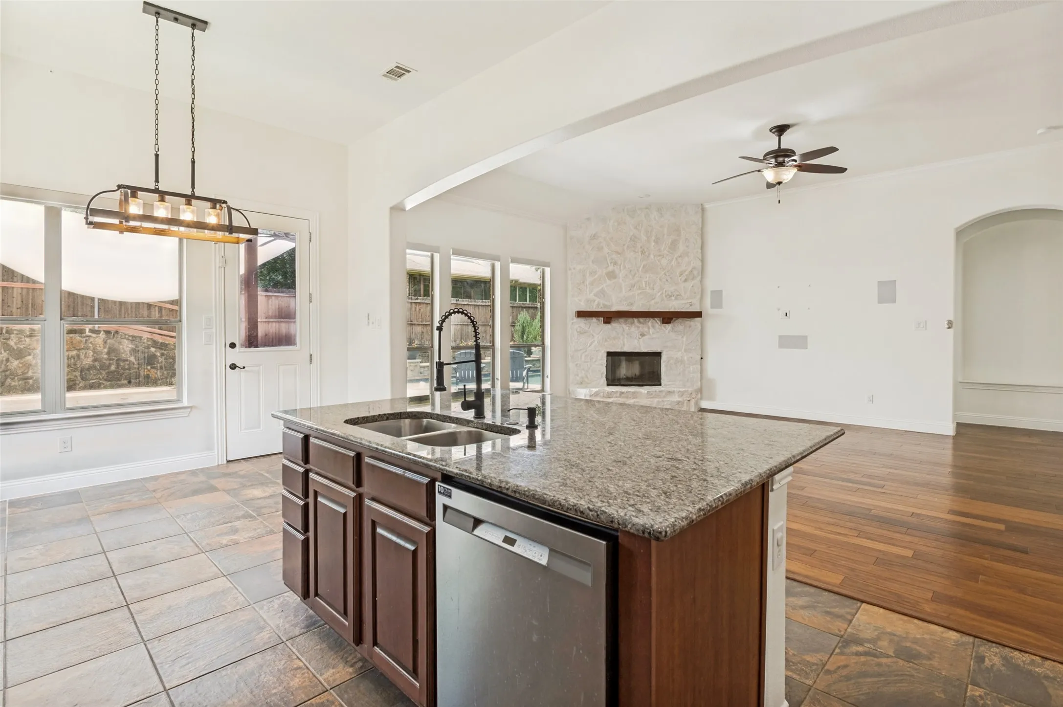 Kitchen island featuring a double-basin sink with a matte black faucet, integrated dishwasher, and granite countertop