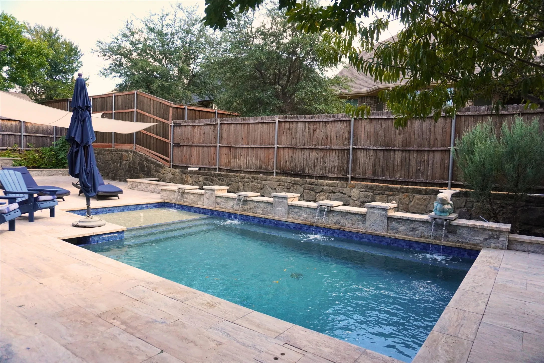 Swimming pool with stone coping, tiled interior, and multiple water features