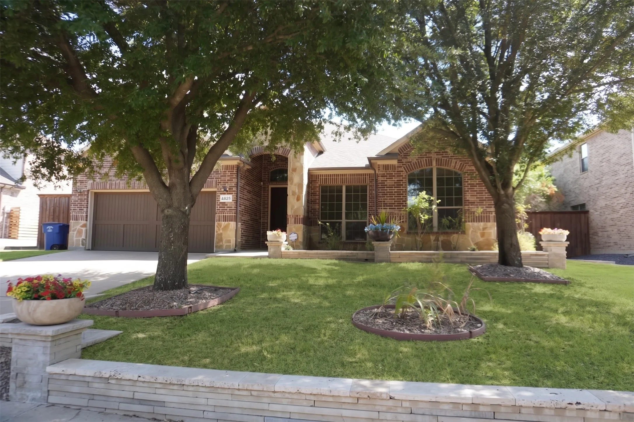 Brick facade with stone accents, arched window, and a two-car garage