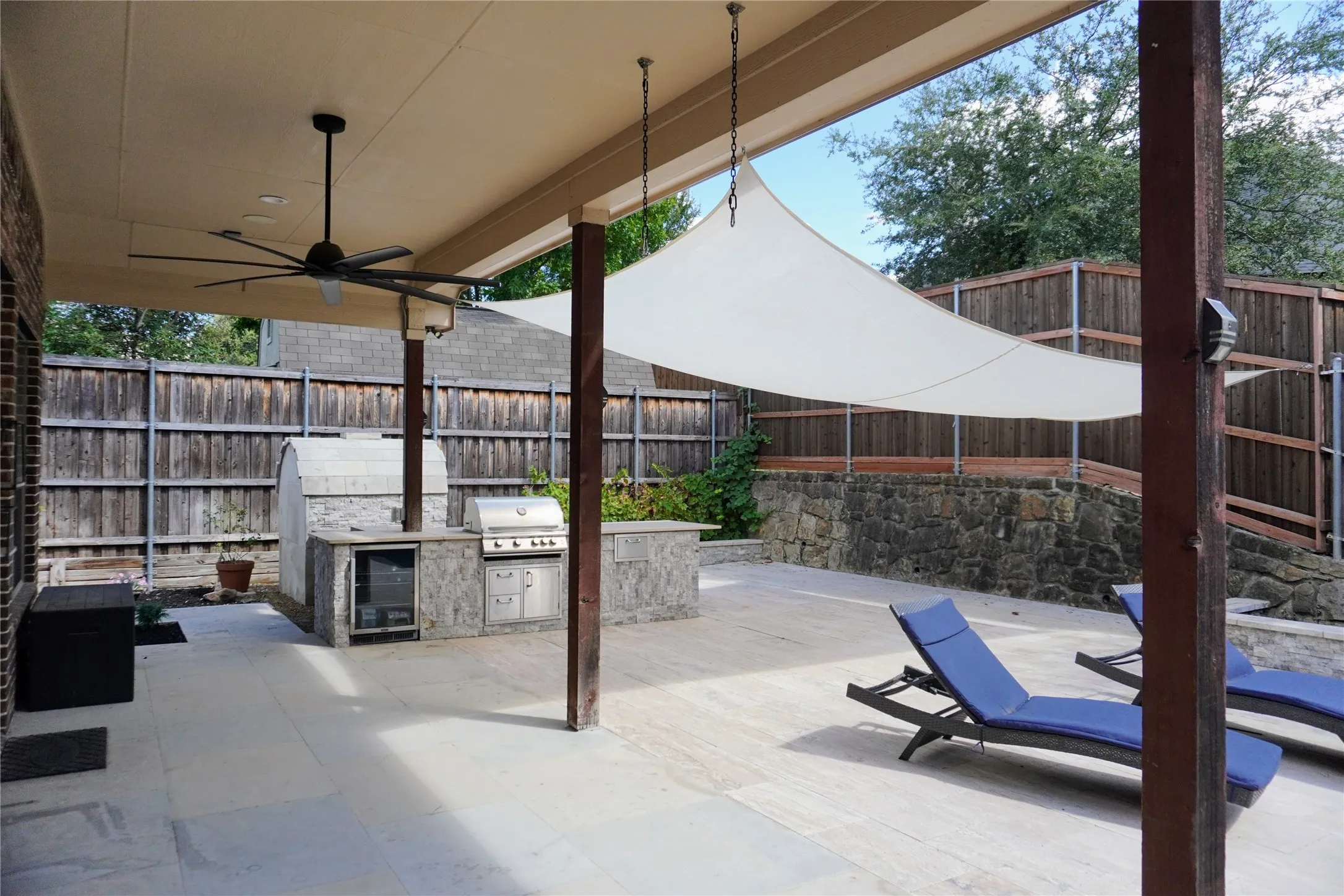 Covered outdoor patio with a ceiling fan, a built-in outdoor kitchen with a grill, and a pizza oven
