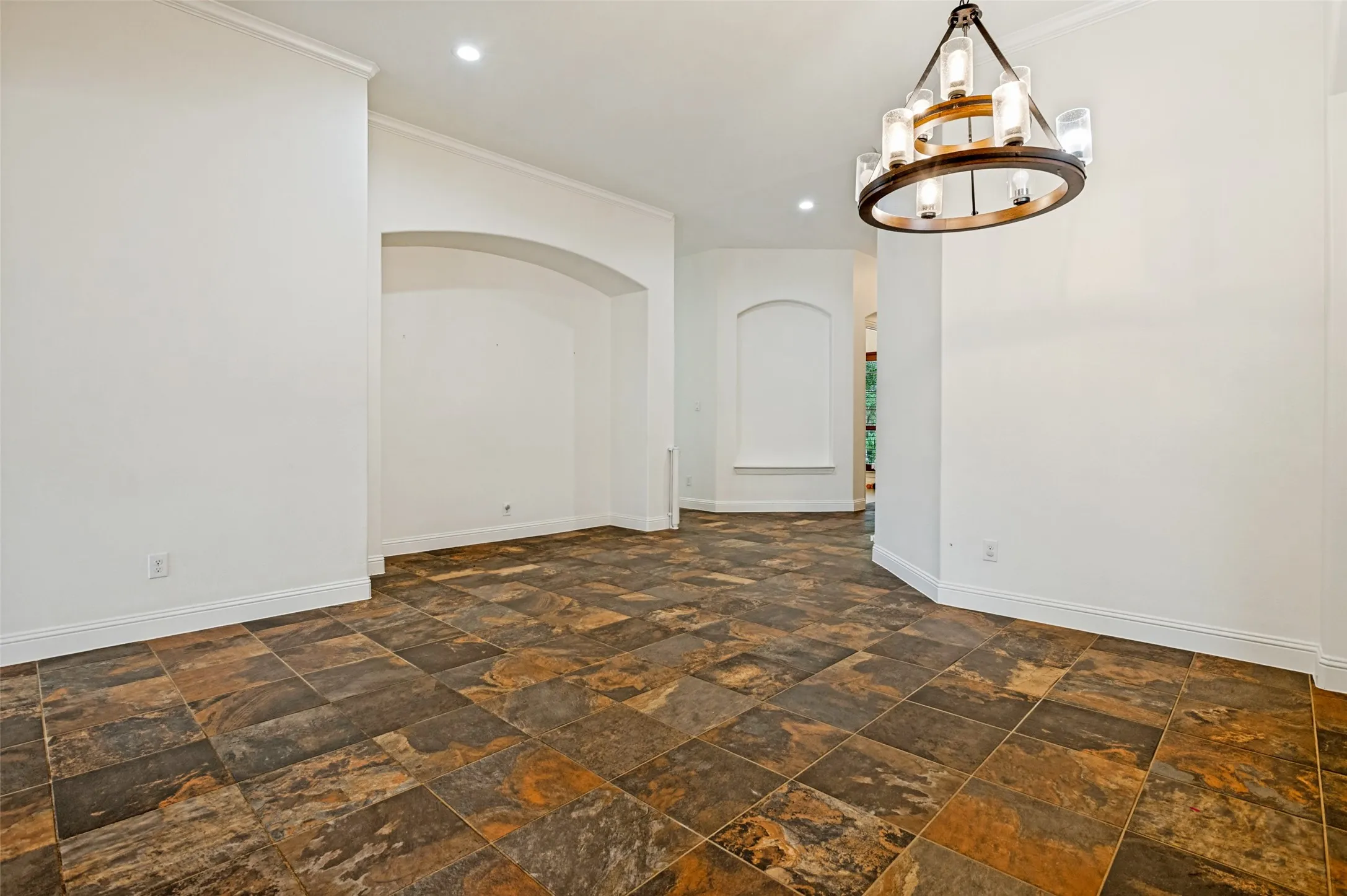 Spacious interior featuring multi-toned square tile flooring, white walls, and a recessed arched wall niche