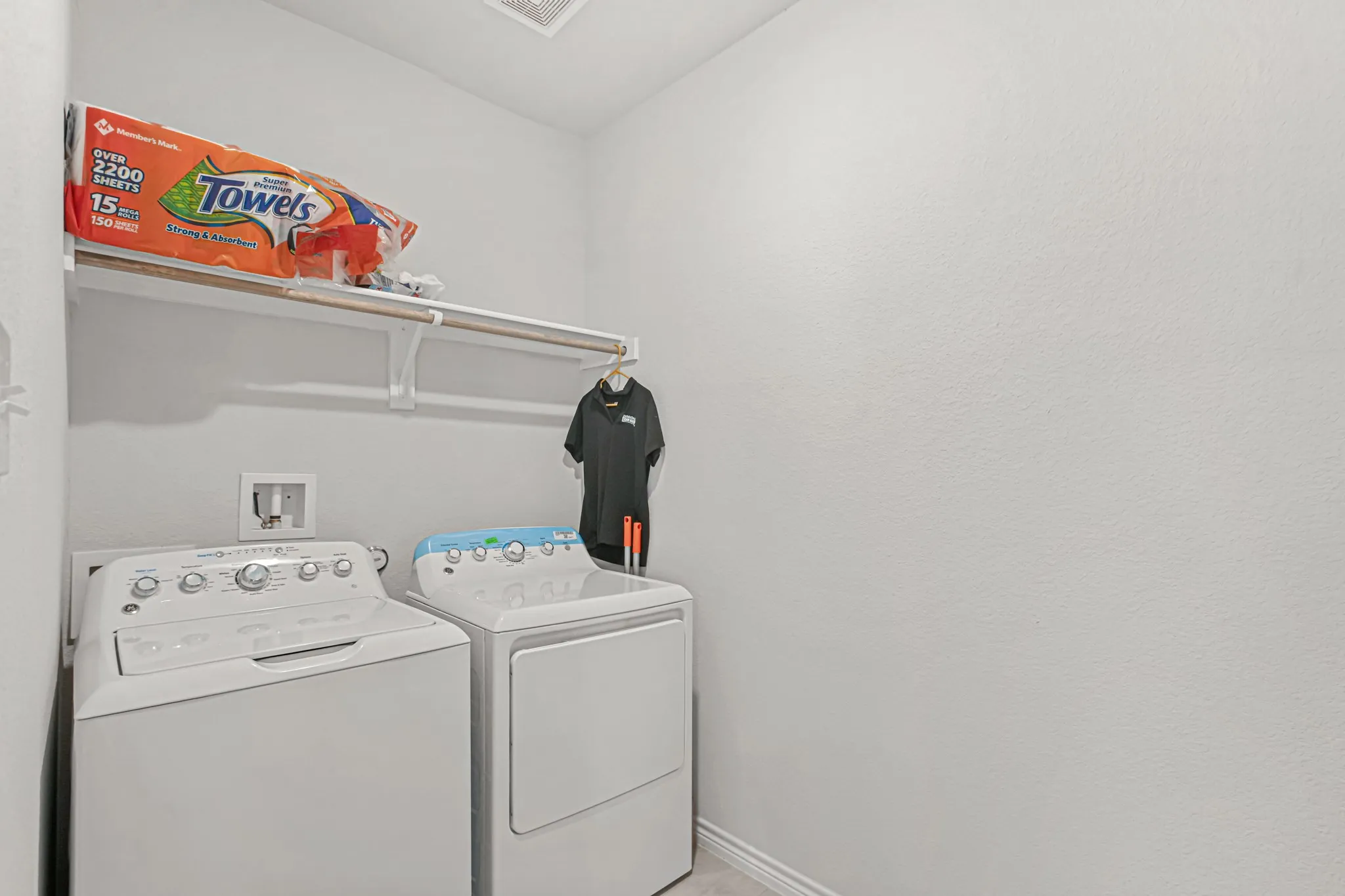 Laundry area featuring a wall-mounted shelf and clothes rod