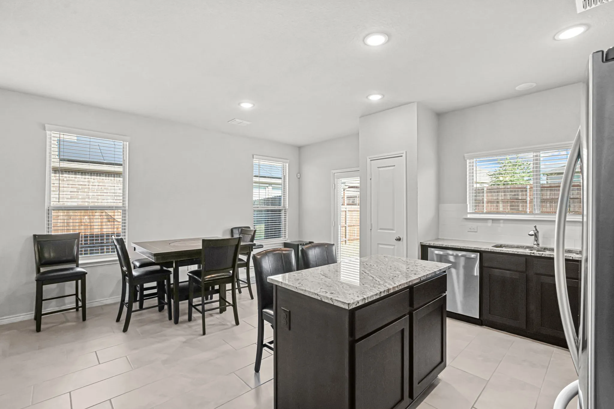 Kitchen featuring a center island with a light-toned countertop, dark wood-finish cabinetry, stainless-steel appliances, and recessed lighting