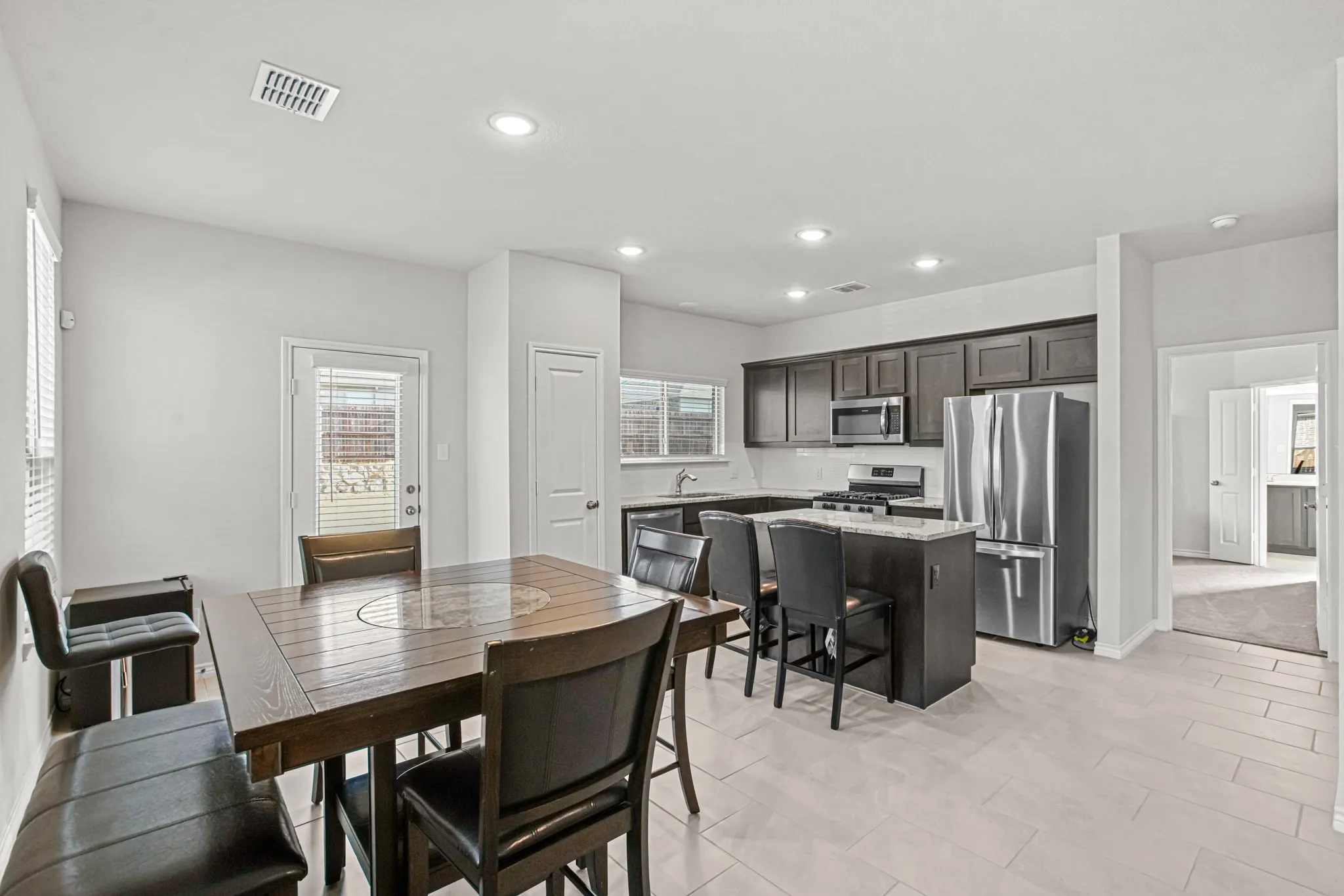 Kitchen featuring dark wood-finish cabinetry, stainless steel appliances, a center island with bar seating, and recessed lighting