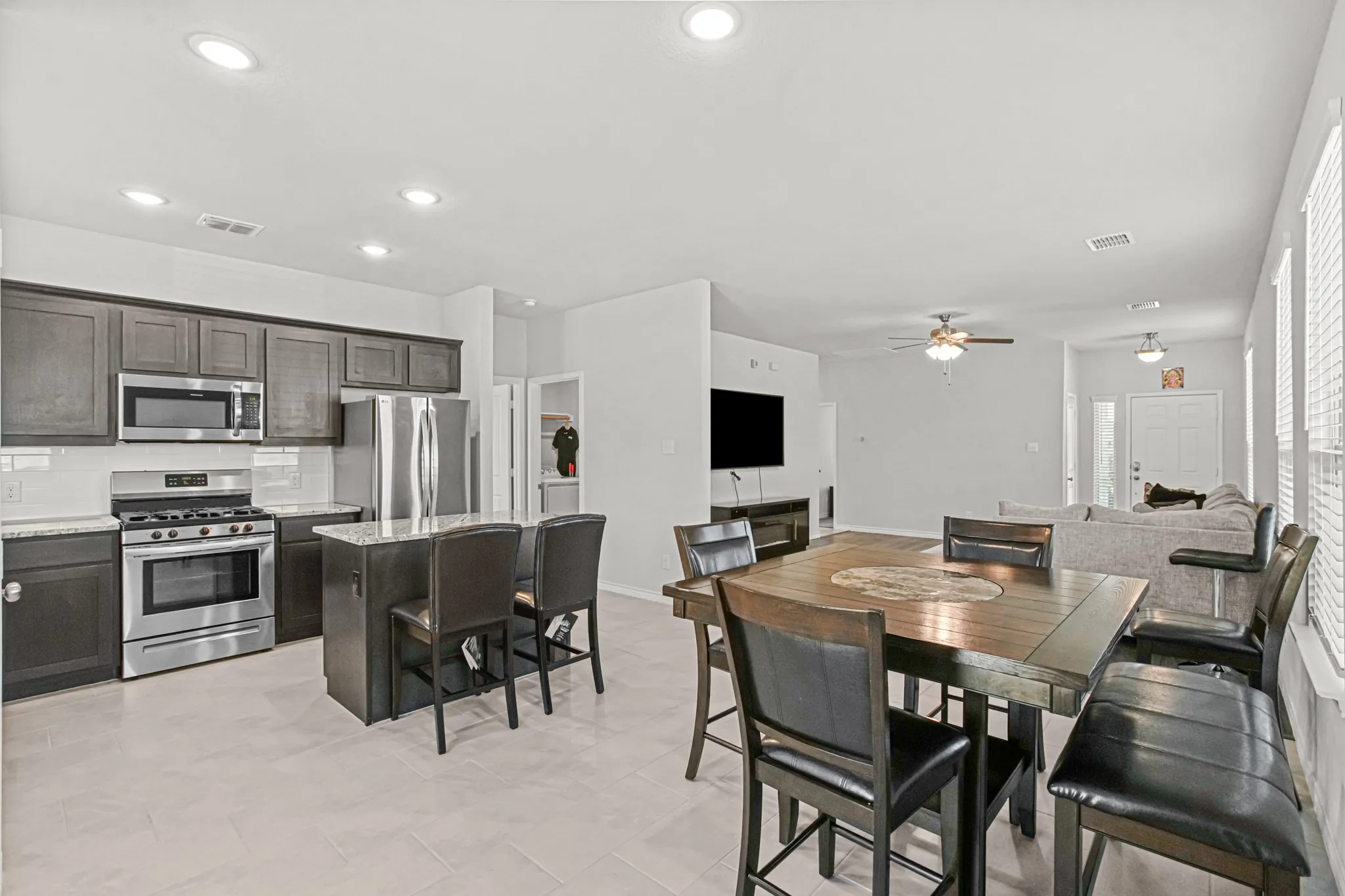 Kitchen featuring dark wood-finish cabinetry, stainless steel appliances, a stone countertop, a tile backsplash, and a central island with seating