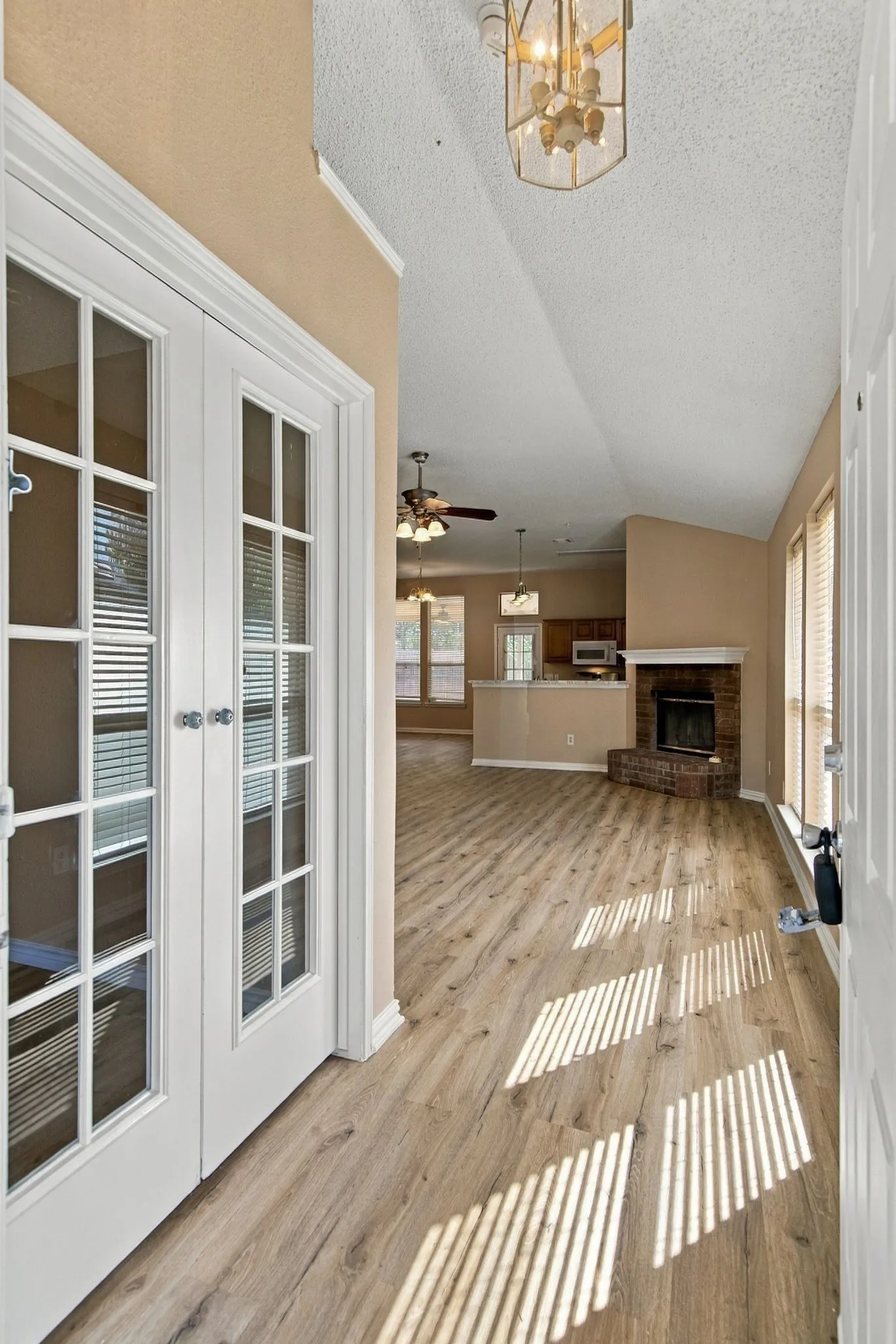 Wood-finish flooring throughout, vaulted ceiling, and a brick fireplace