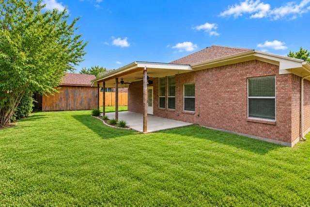 Expansive backyard featuring a manicured lawn, a covered patio with integrated lighting, and a detached wooden shed, grass Greened