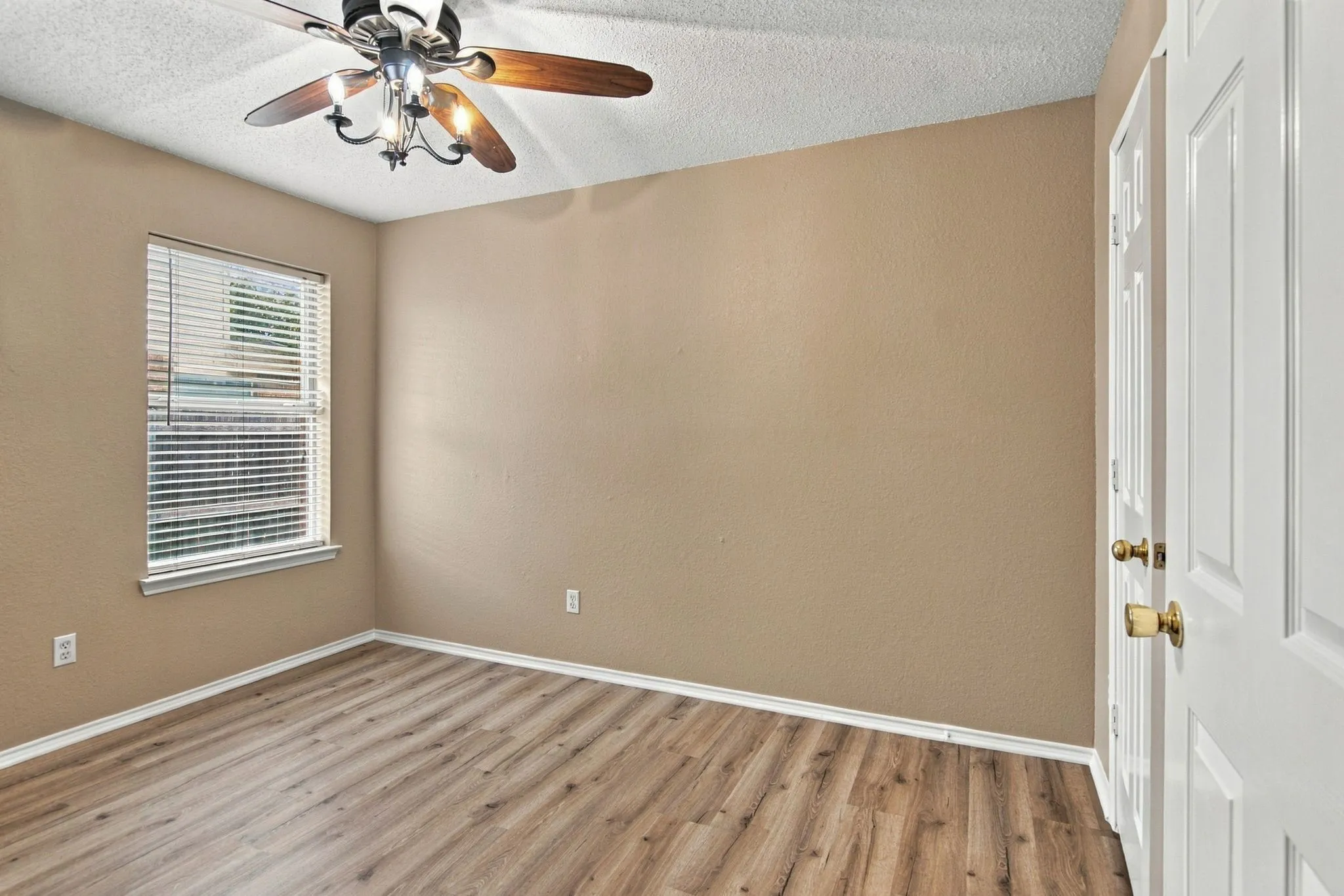 Wood-finish flooring, ceiling fan with light fixture, window with blinds, and paneled interior door