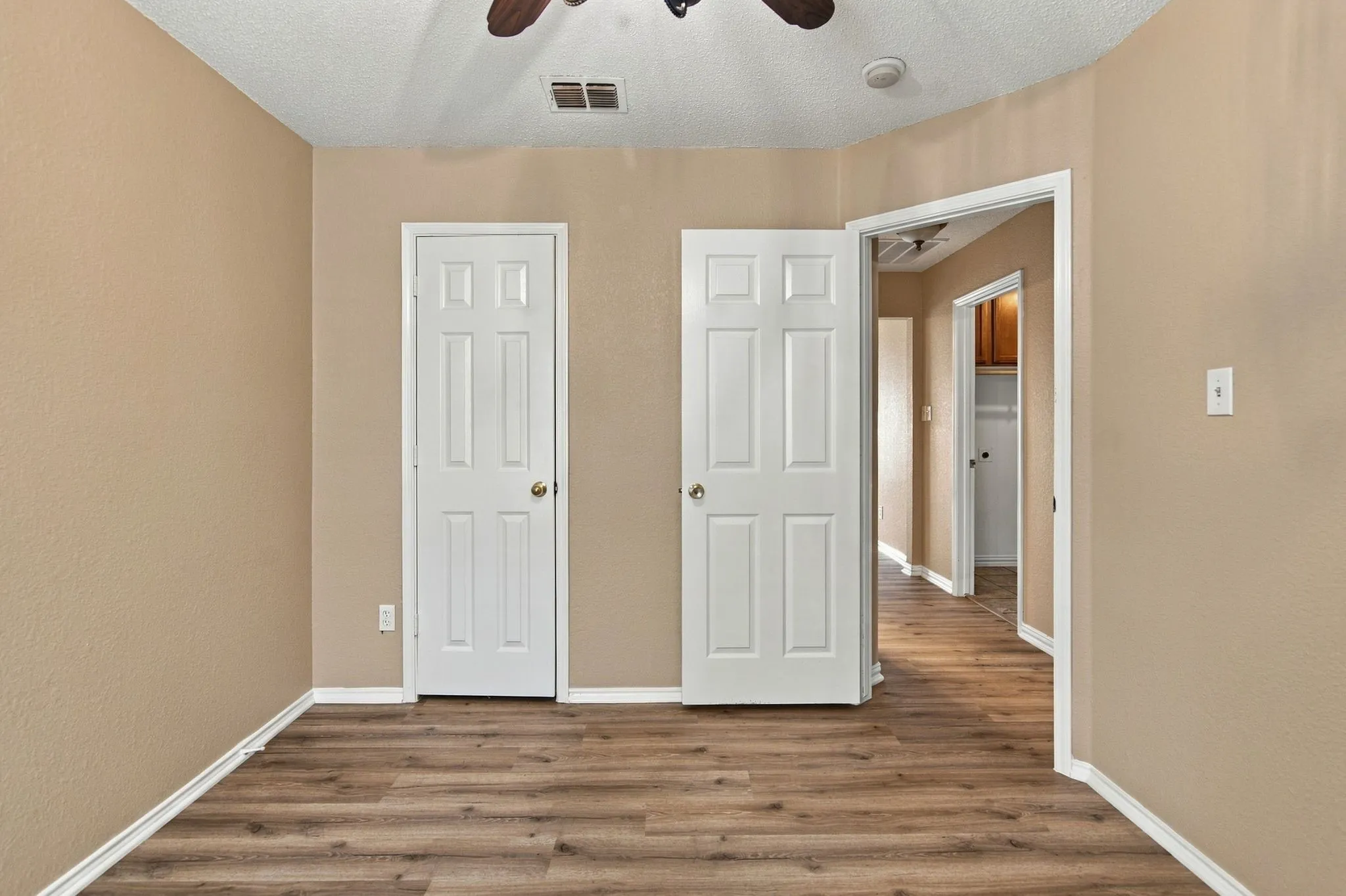 Wood-finish flooring throughout, neutral wall tones, and white interior doors