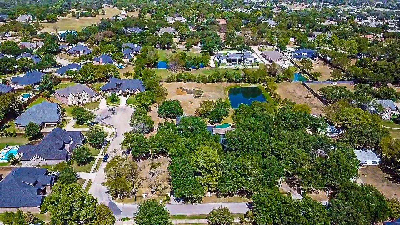Neighborhood featuring extensive tree canopy, residential properties with dark-colored roofs, and winding street patterns