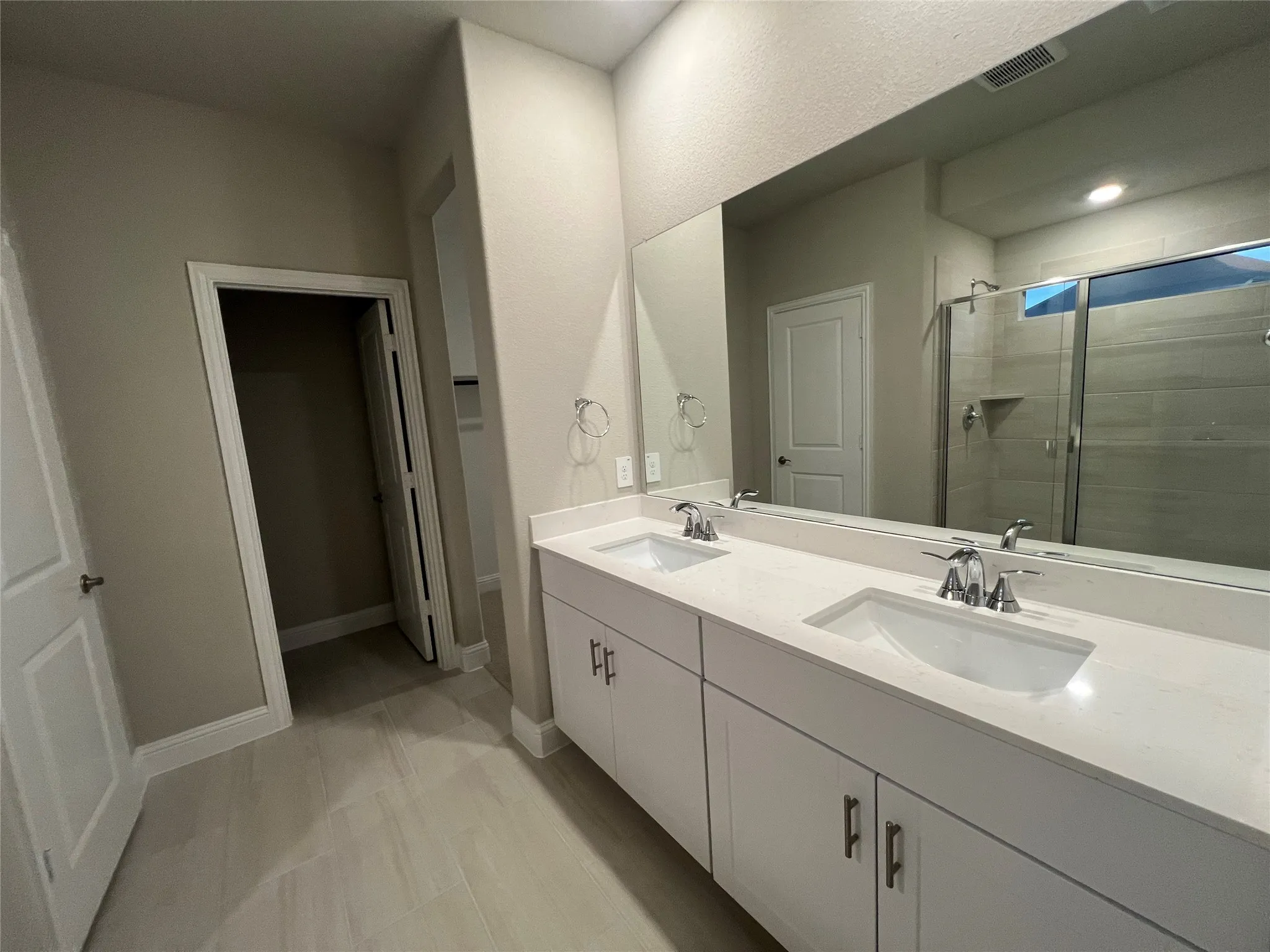 Dual vanity with undermount sinks, stone countertops, and chrome fixtures